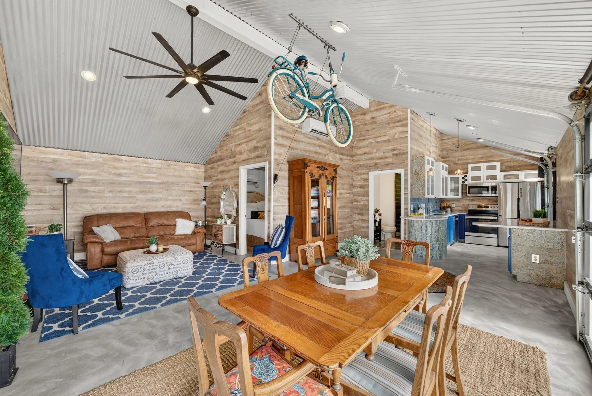 Open-concept living space featuring wood-finish accent walls, corrugated metal vaulted ceiling, and polished concrete flooring