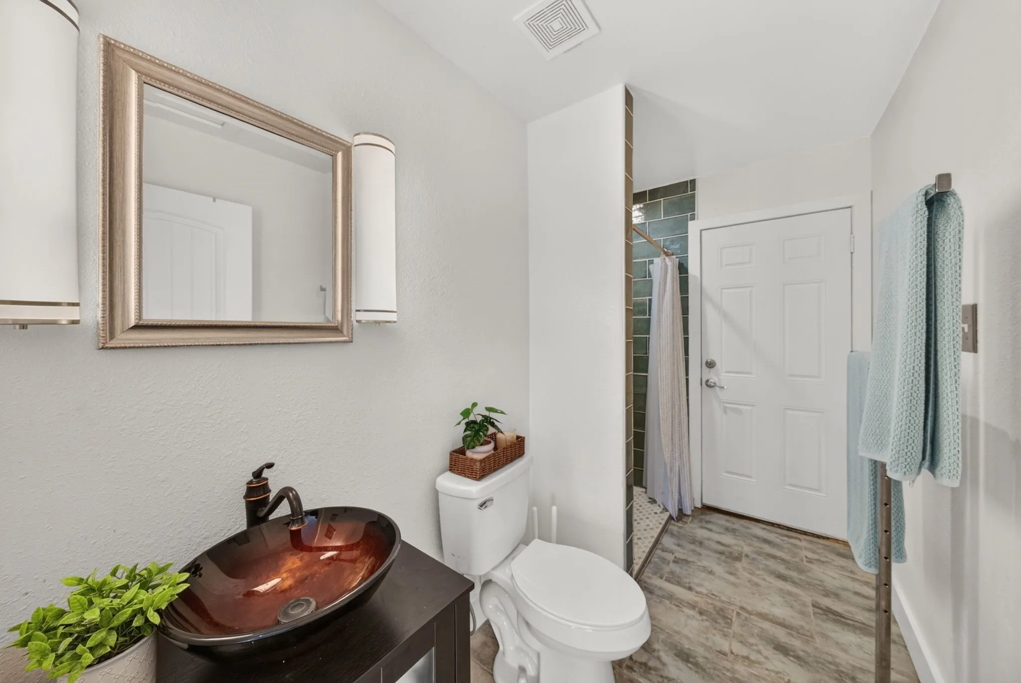 Contemporary bathroom featuring a vessel sink with a dark bronze faucet, a framed mirror, and two wall sconces