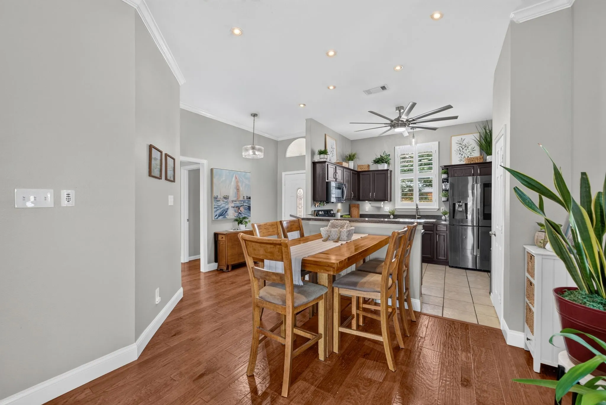 Open-concept dining area featuring wood-finish flooring, crown molding, and recessed lighting