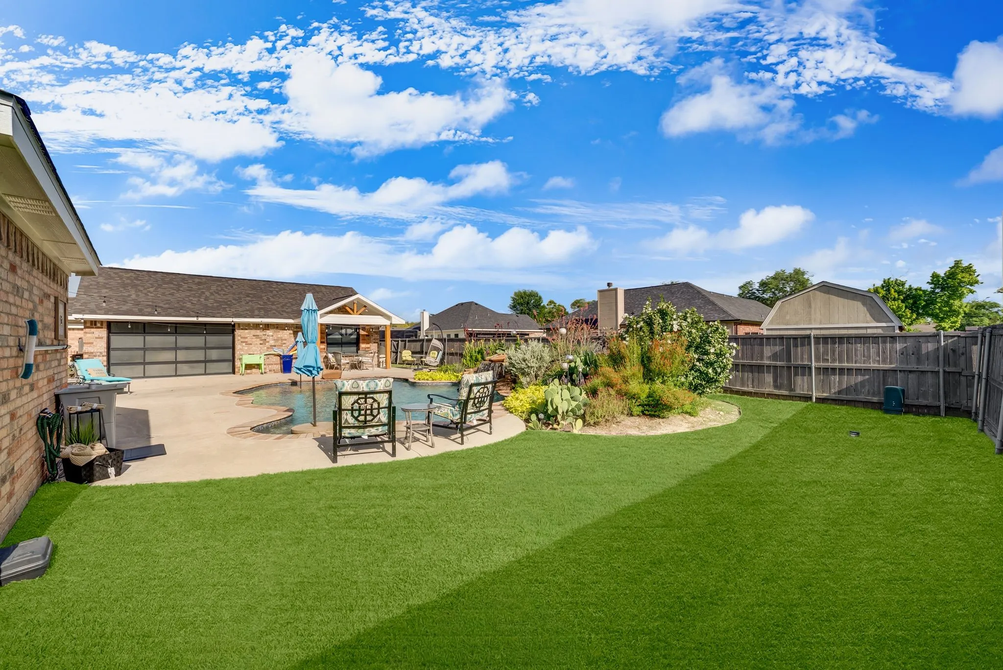 Expansive backyard featuring a large swimming pool, concrete patio, and a dedicated artificial turf area