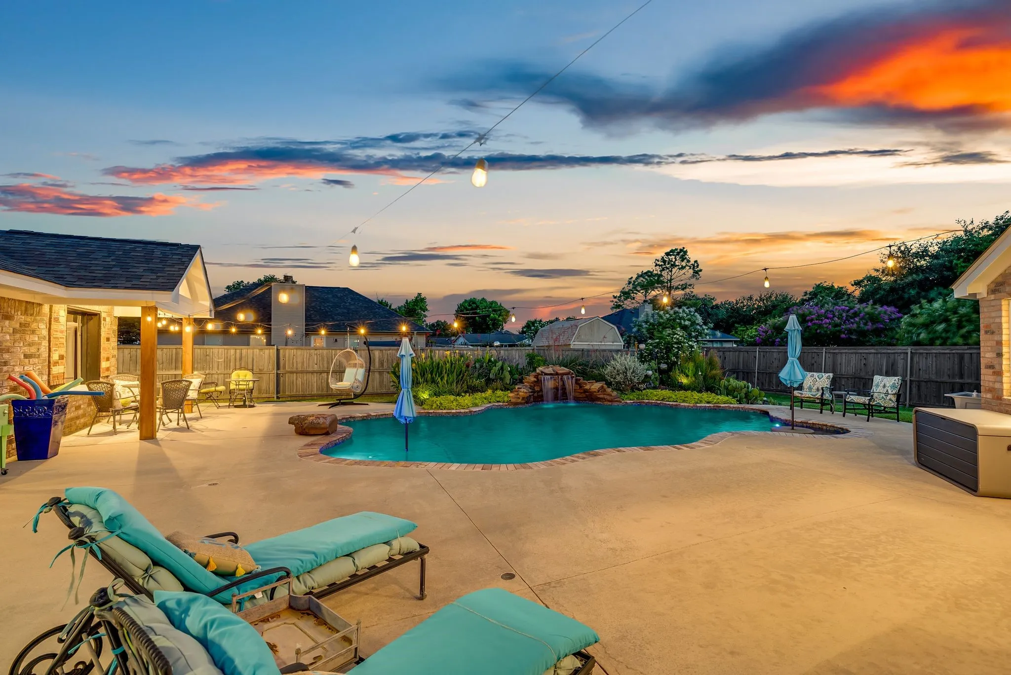 Expansive backyard featuring a freeform swimming pool, integrated rock waterfall, and perimeter landscaping