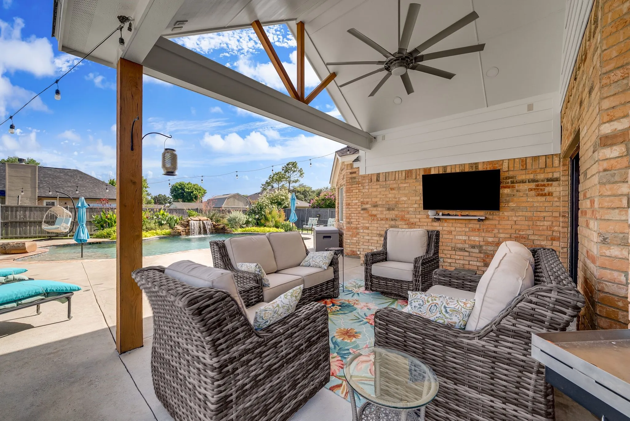 Covered patio featuring a sloped ceiling, exposed wood beams, and a large ceiling fan