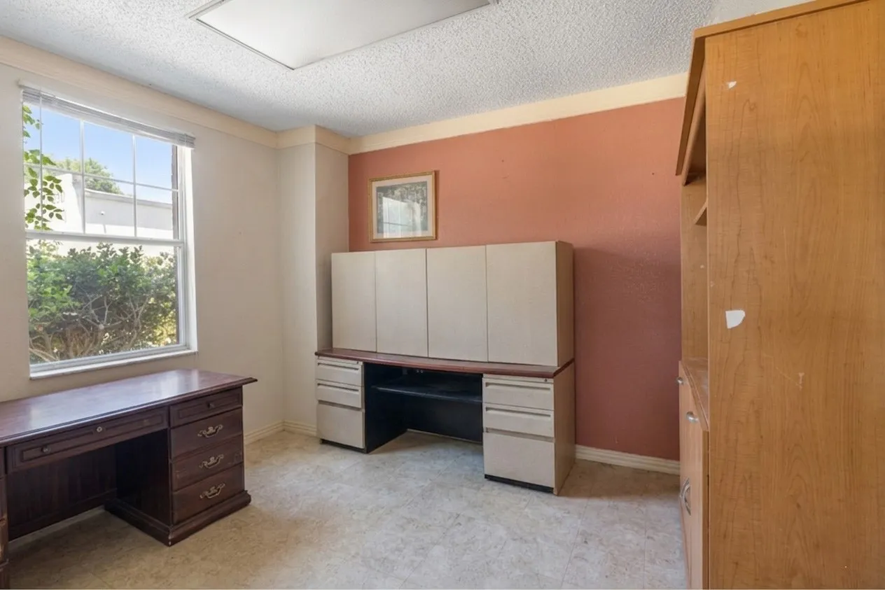 Room featuring a window with natural light, textured ceiling, light-toned carpet, and a warm-toned accent wall