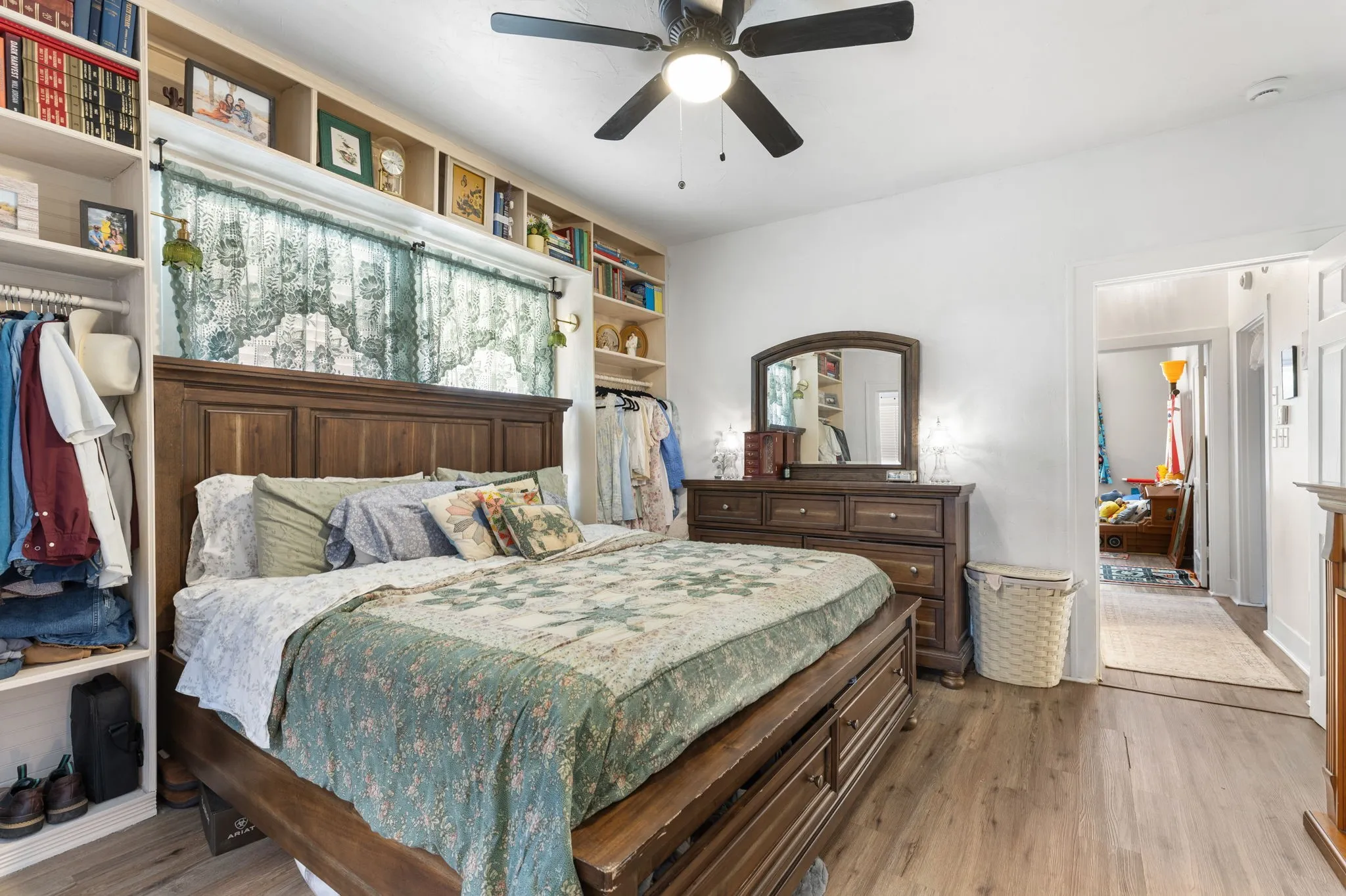 Primary bedroom featuring built-in shelving, window treatments and wood-finish flooring