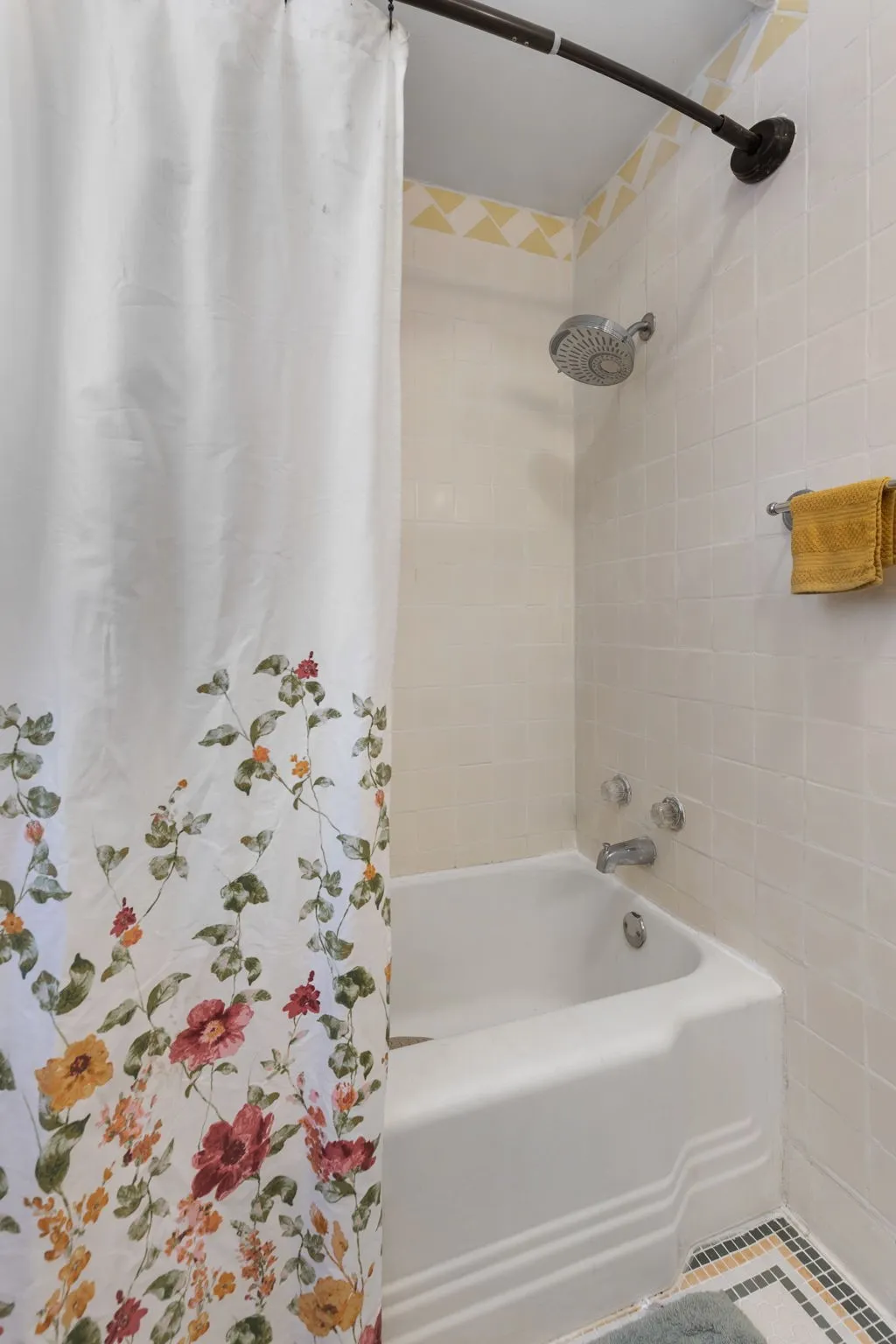 White subway tile shower surround with a built-in tub, chrome fixtures, and a decorative tile border
