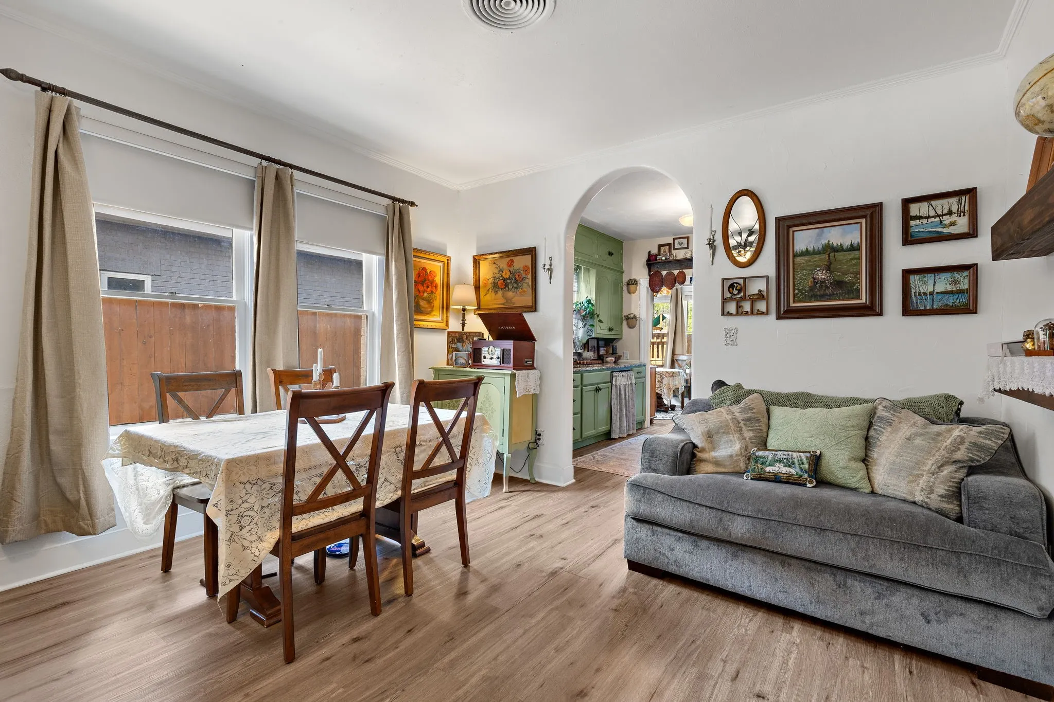 Open-concept living and dining area with wood-like flooring and natural light