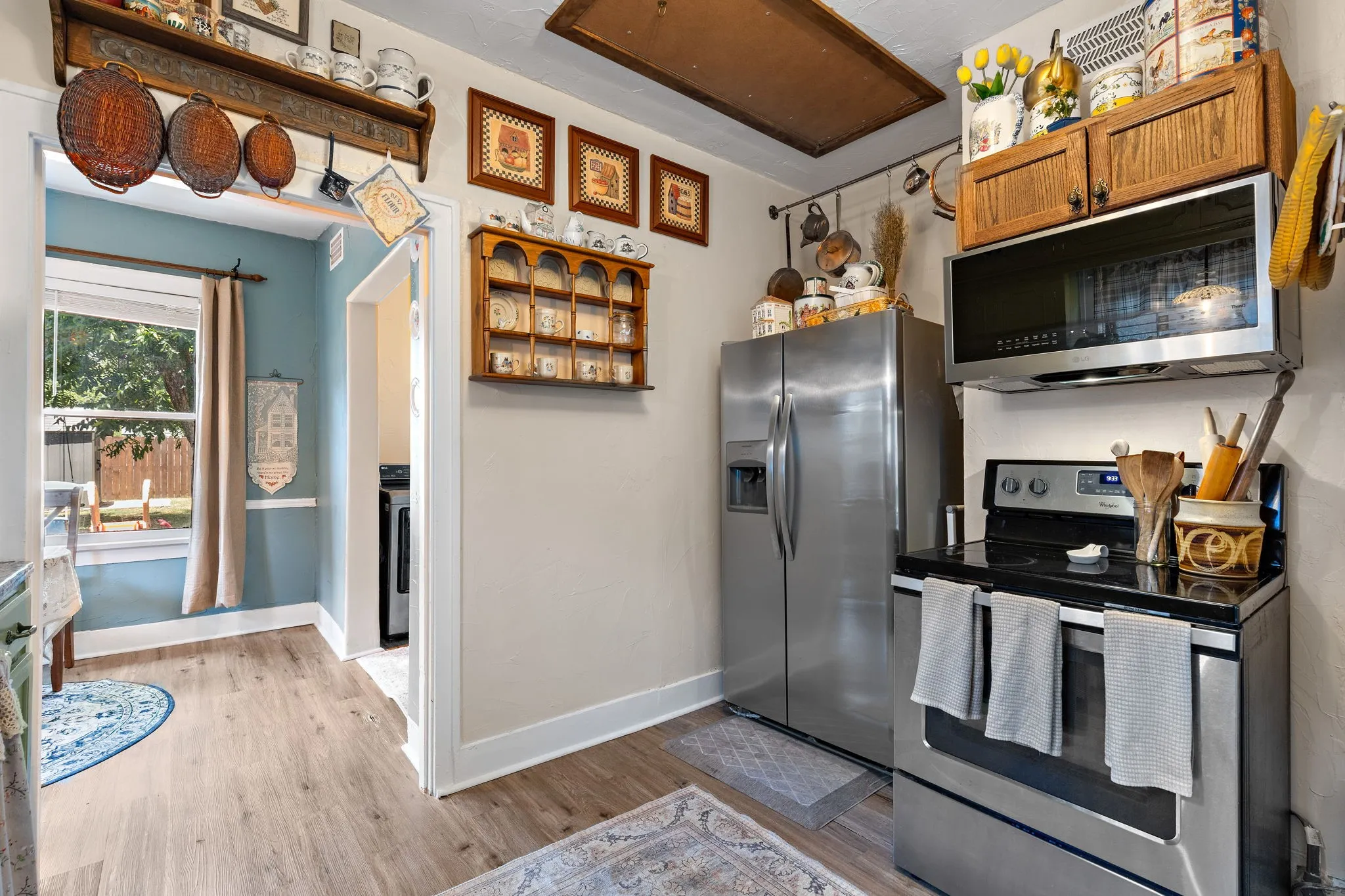 Galley kitchen featuring stainless steel appliances, wood-like flooring and a window with exterior views