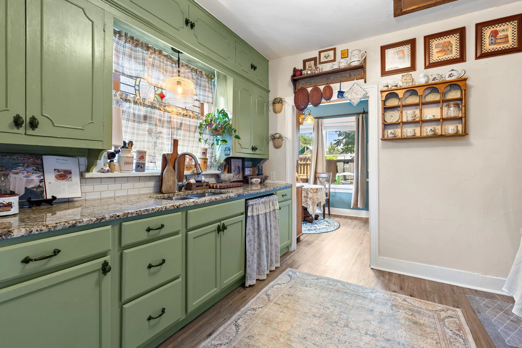 Kitchen featuring sage green cabinetry, granite-look countertops, and a white subway tile backsplash