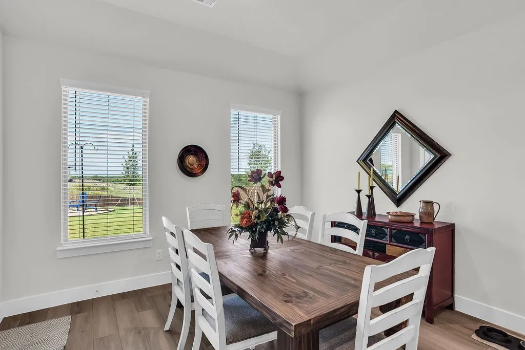 Dining/Breakfast room featuring wood-finish flooring, white walls, and backyard views opens to Kitchen and Living rooms