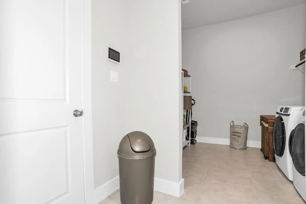 Oversized mudroom/laundry area featuring light-toned tile flooring, electric connections and extra drying space.