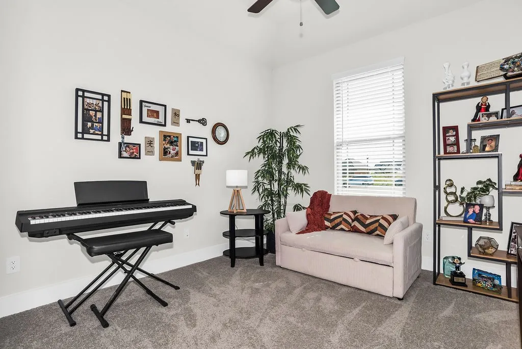 Bright interior room with ceiling fan, carpeted flooring, and light-colored walls