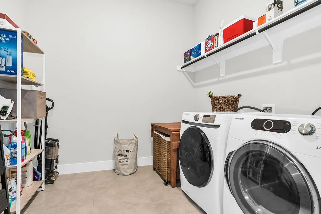 Oversized mudroom/laundry area featuring light-toned tile flooring, electric connections and extra drying space.