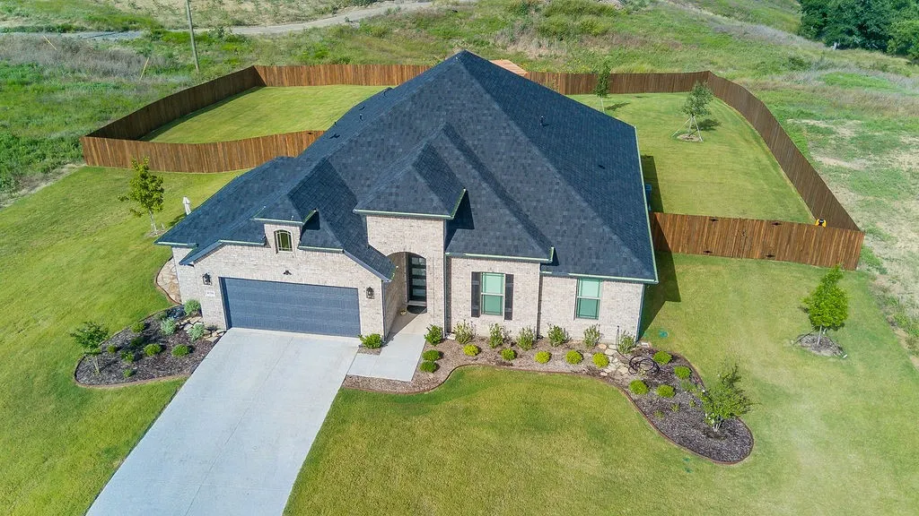 Spacious backyard featuring a wood pergola over a circular stone patio, raised garden beds, and a full privacy fence