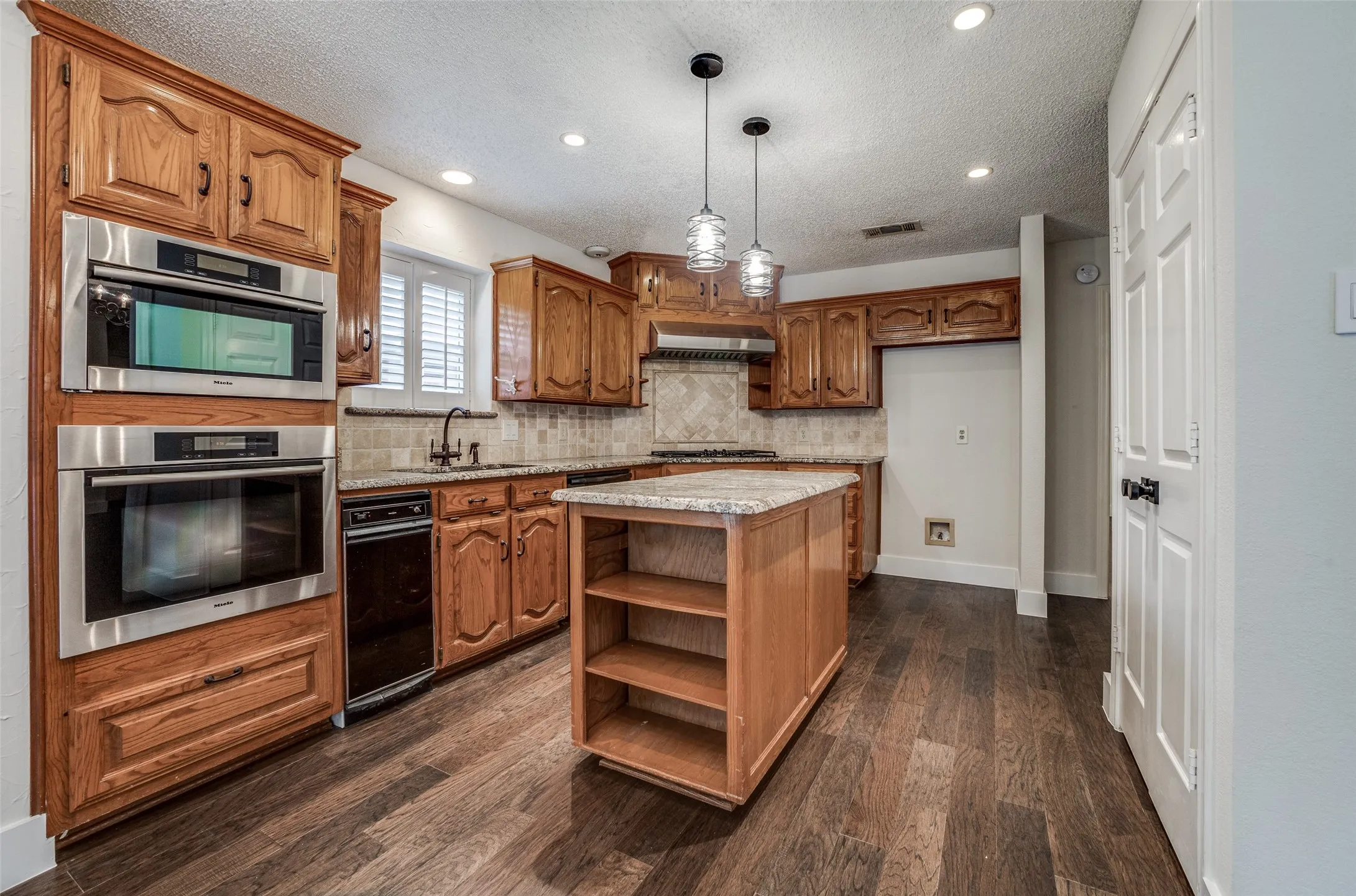 Kitchen featuring wood-finish flooring, recessed lighting, and a center island with open shelving