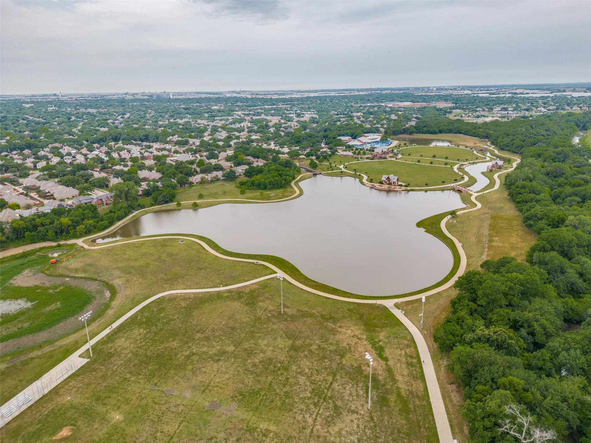 Aerial perspective showcasing a large body of water surrounded by paved walking paths and abundant green space