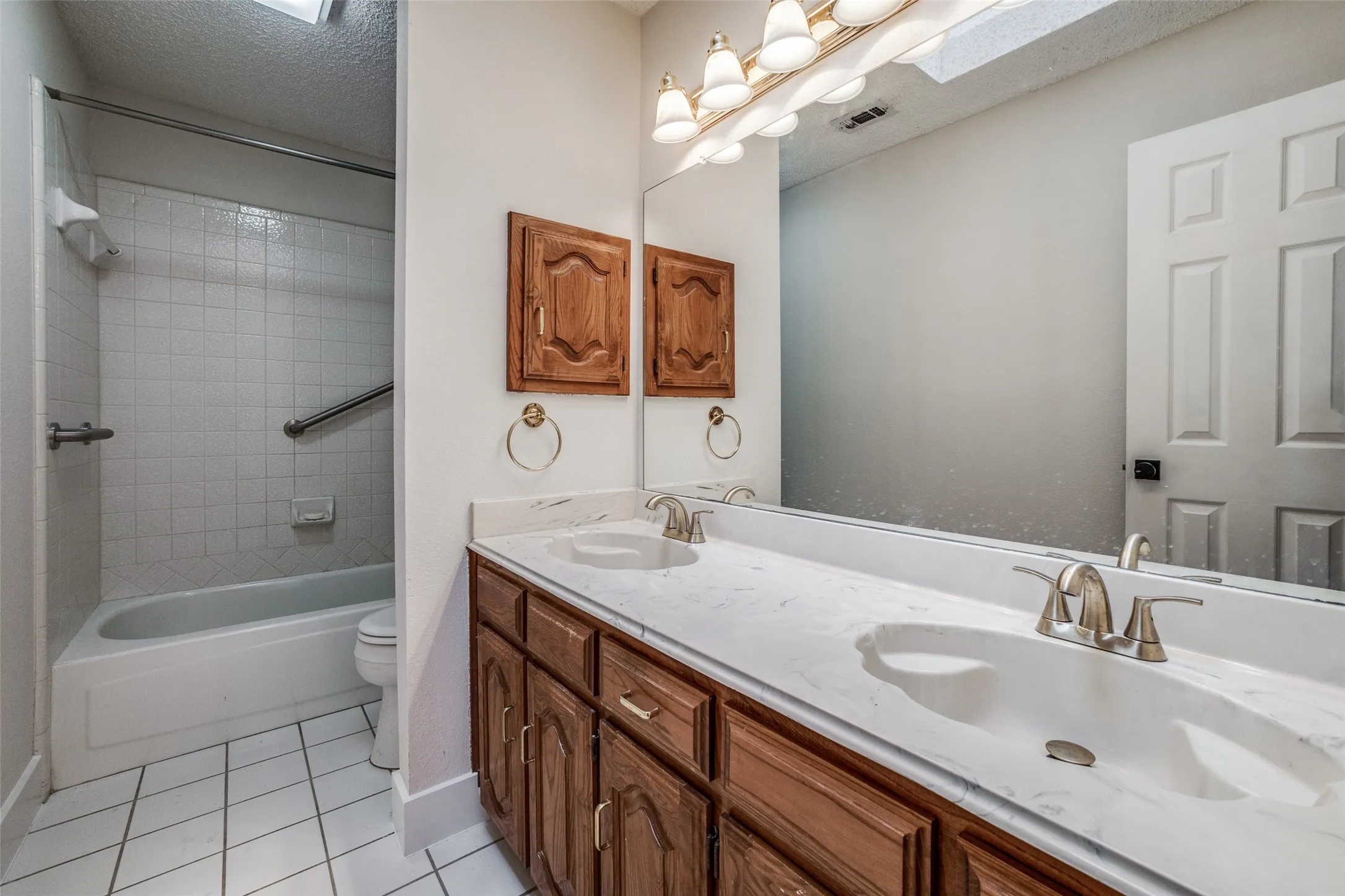 Bathroom featuring a dual sink vanity with a white countertop and wood-finish cabinetry