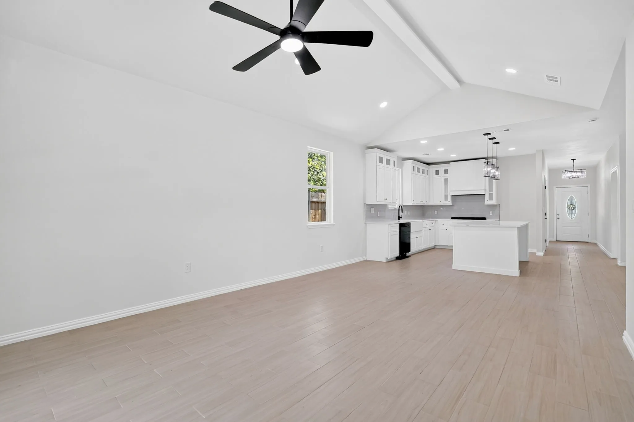 Open-concept living area featuring light wood-finish flooring and a vaulted ceiling with a ceiling fan