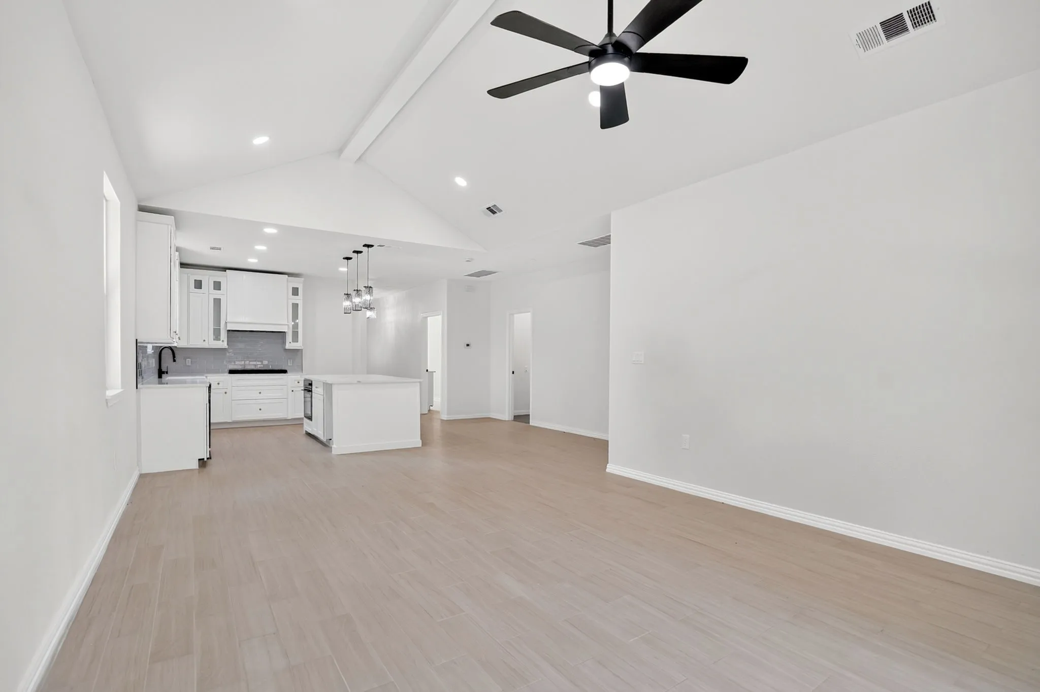 Open-concept living space featuring wood-finish flooring and a vaulted ceiling