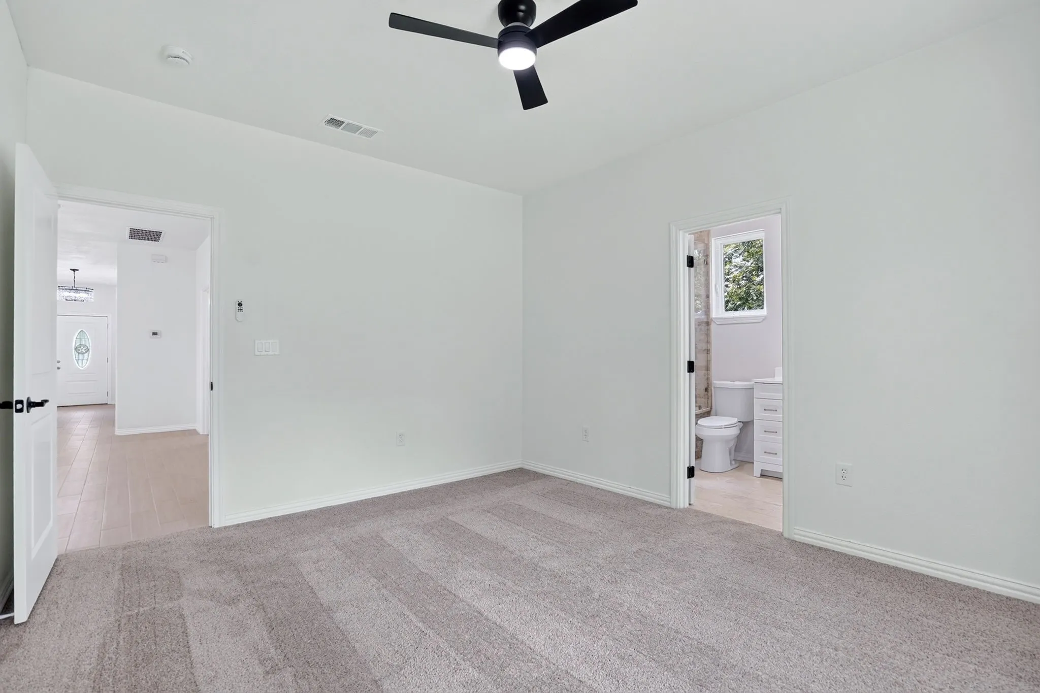 Carpeted interior space featuring a matte black ceiling fan, white trim, and light-toned walls