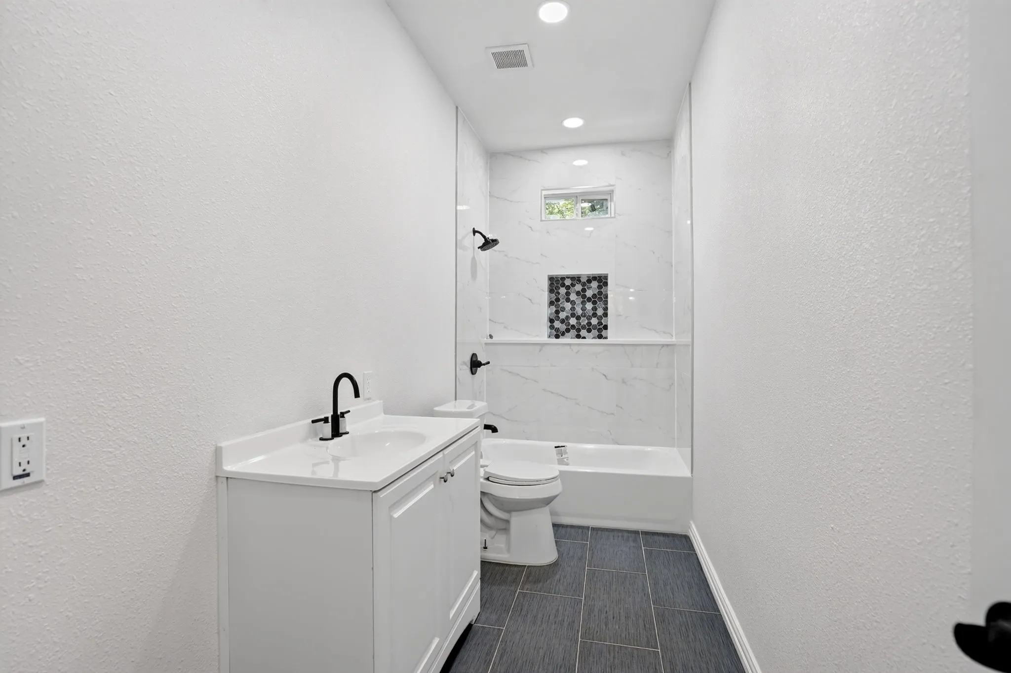 White vanity with a solid surface countertop and matte black faucet