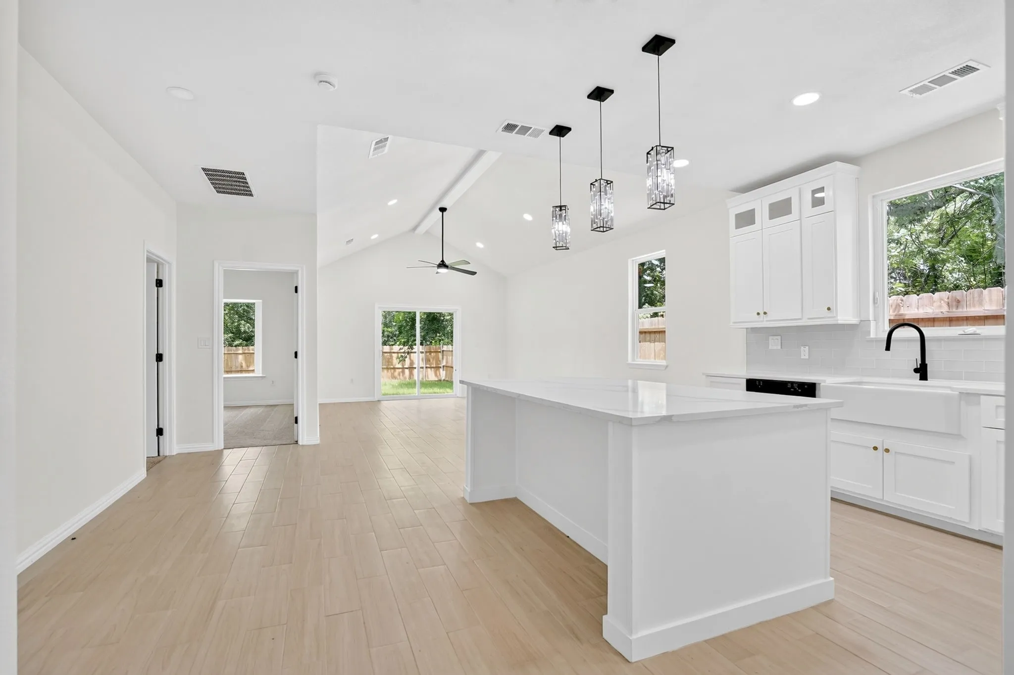 Open-concept living space featuring wood-finish flooring, a vaulted ceiling, and an expansive kitchen island with a white countertop