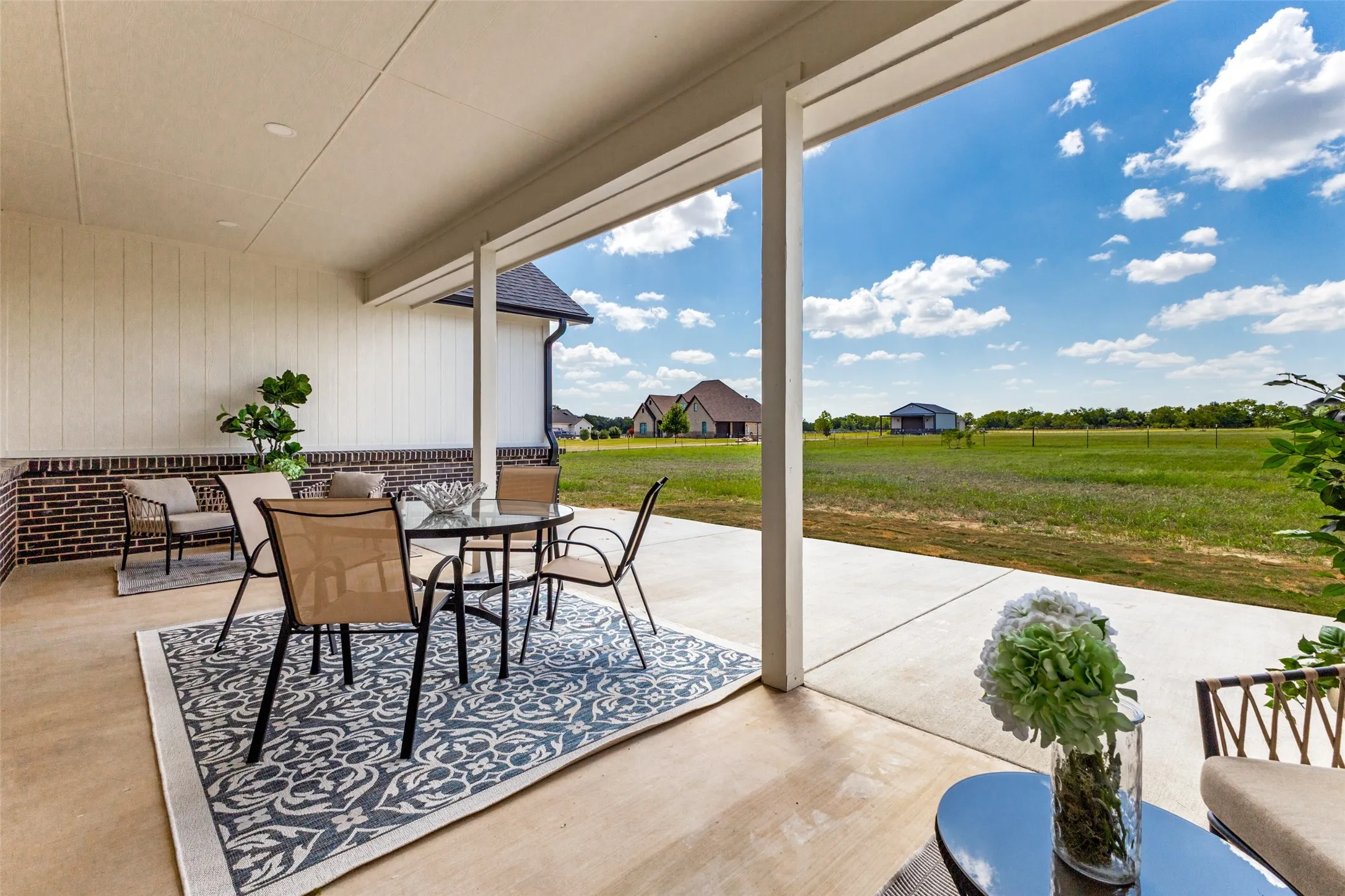 Covered patio with a concrete surface, brick wainscoting, and white vertical siding