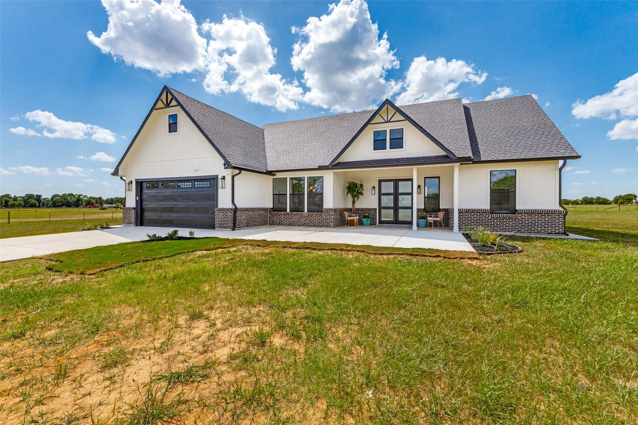 Modern farmhouse exterior featuring white siding and dark brick accents