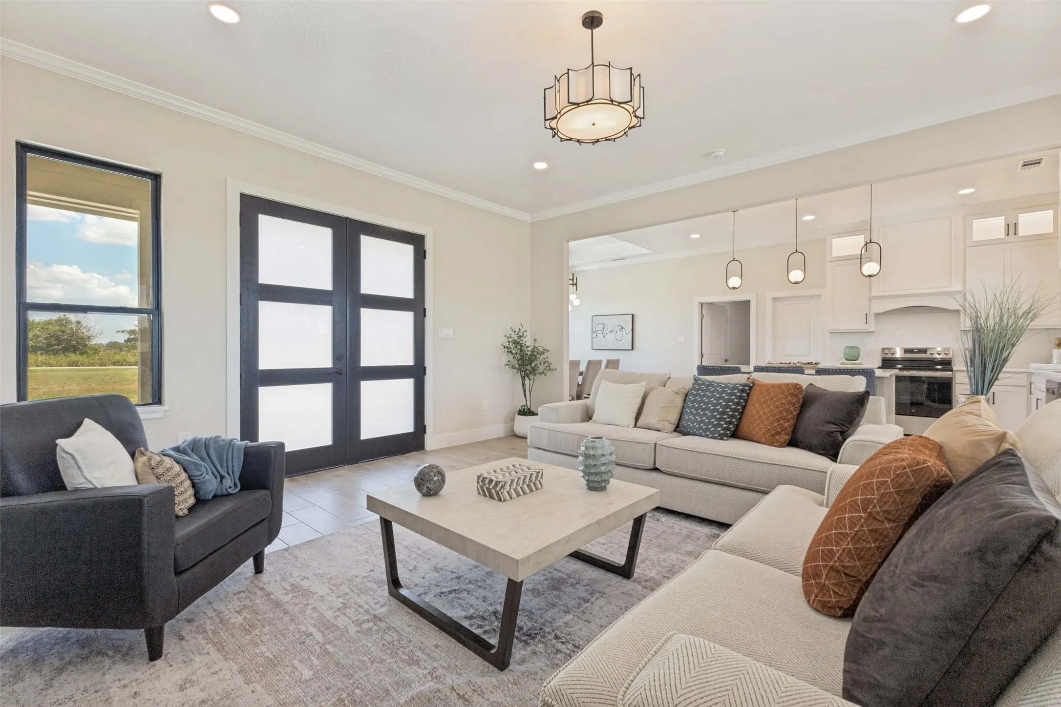 Spacious open-concept living area featuring a modern chandelier, recessed lighting, and crown molding