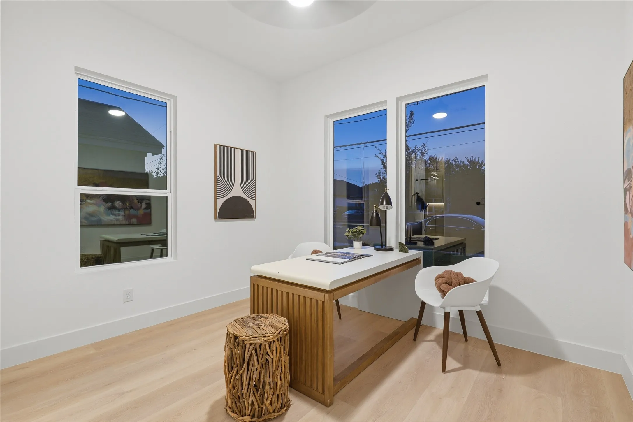 Bright room featuring two large windows, light wood-finish flooring, white walls, and a contemporary ceiling light fixture