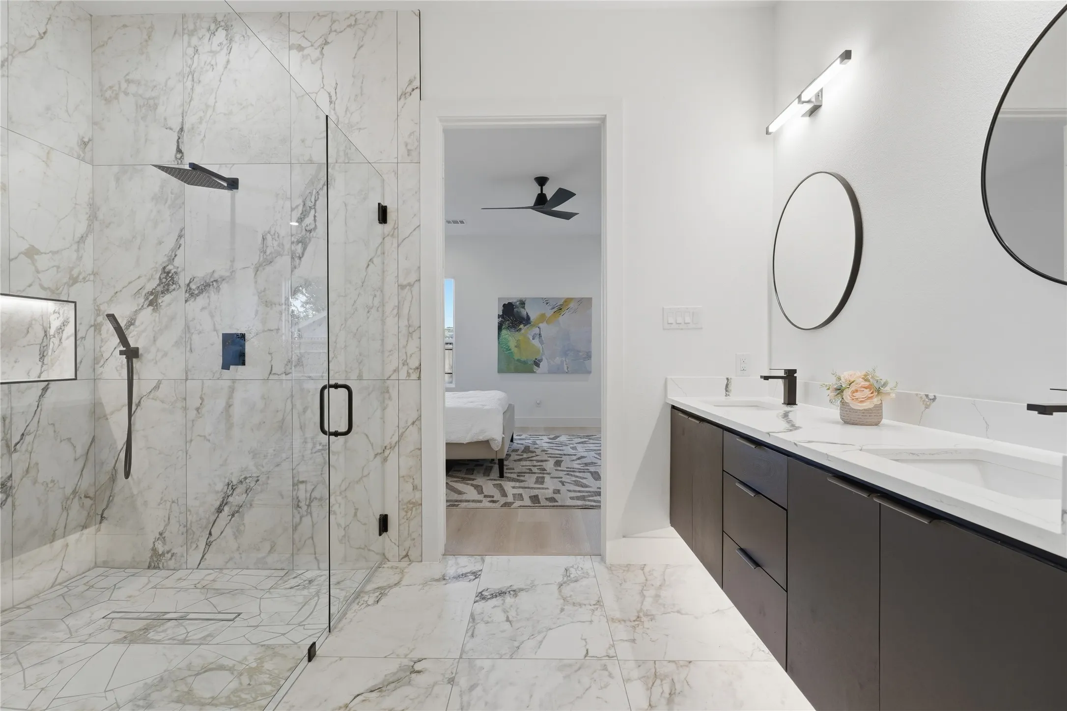 Walk-in shower with full-height marble-look tile, frameless glass enclosure, and matte black fixtures