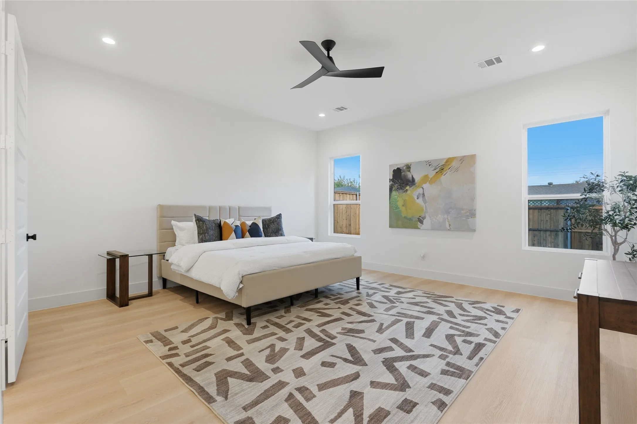 Spacious room featuring light wood-finish flooring, recessed lighting, and a modern ceiling fan