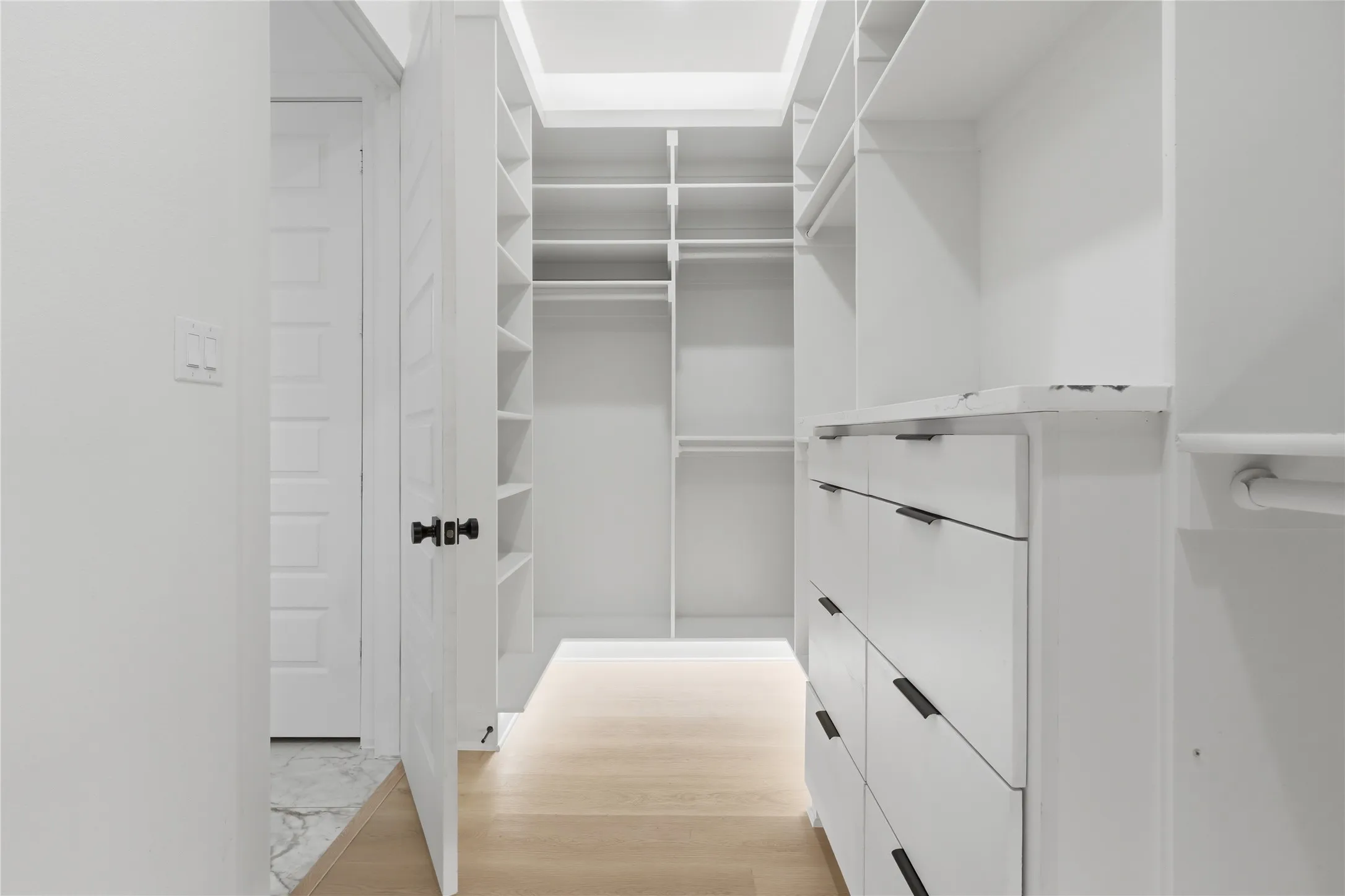 Custom closet organization system featuring white cabinetry and shelving