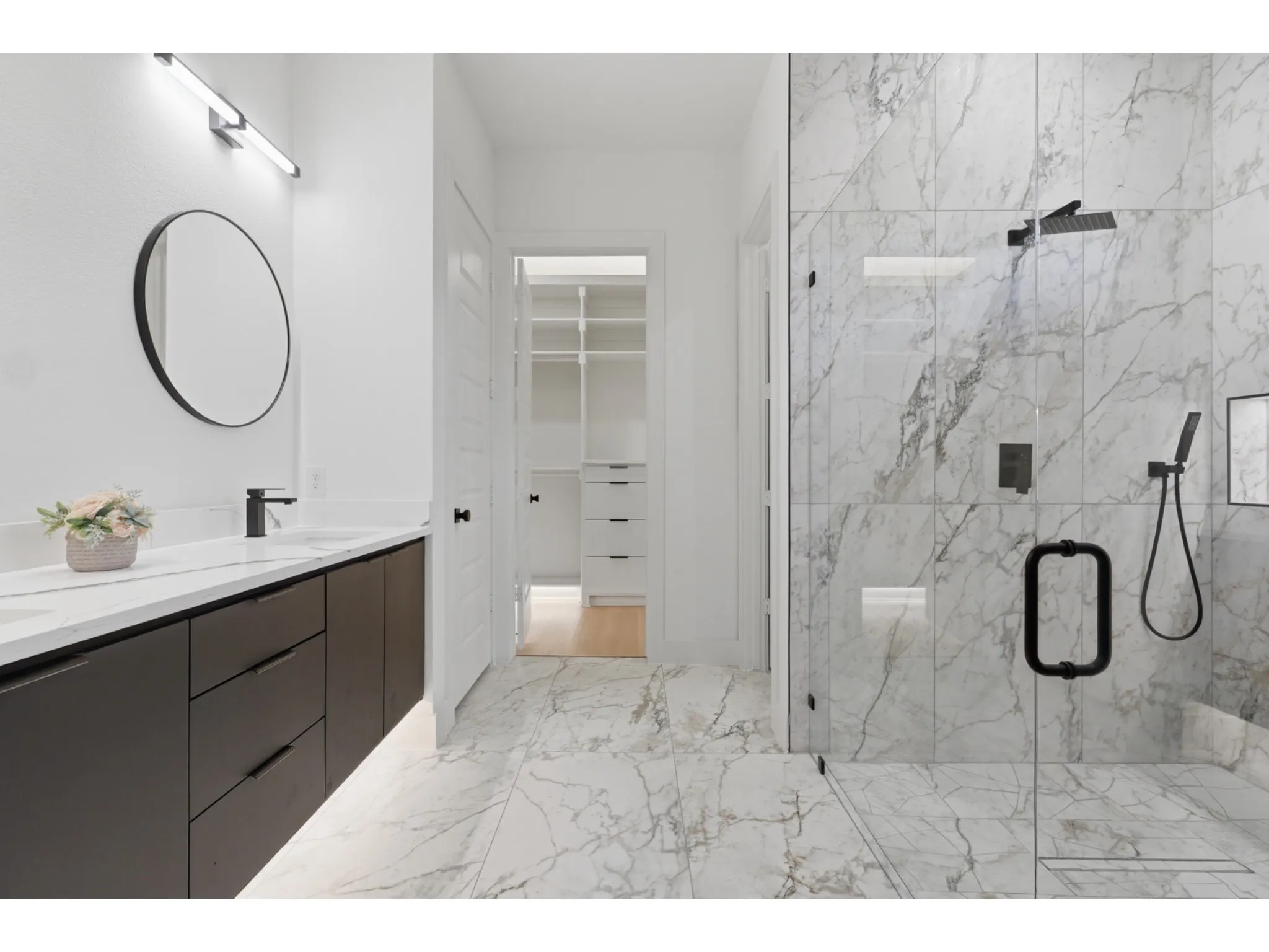 Contemporary bathroom featuring a spacious glass-enclosed shower with black fixtures and large format marble-look tile