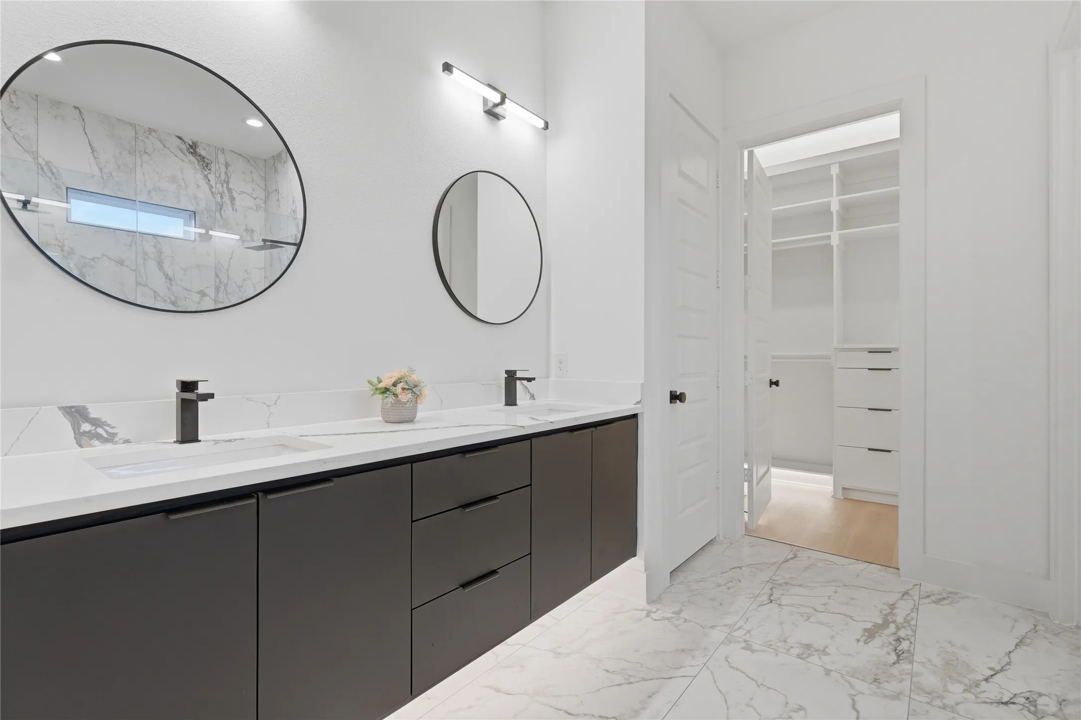 Bathroom featuring a dual vanity with dark flat-panel cabinetry, white countertops, and integrated rectangular sinks