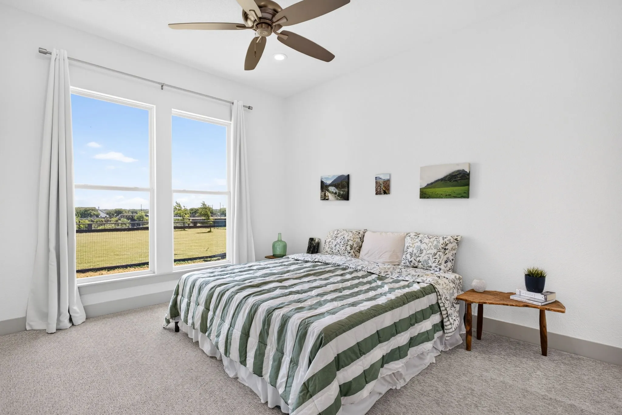 Bright bedroom featuring two large windows, an overhead ceiling fan, white walls, and light-colored carpeting