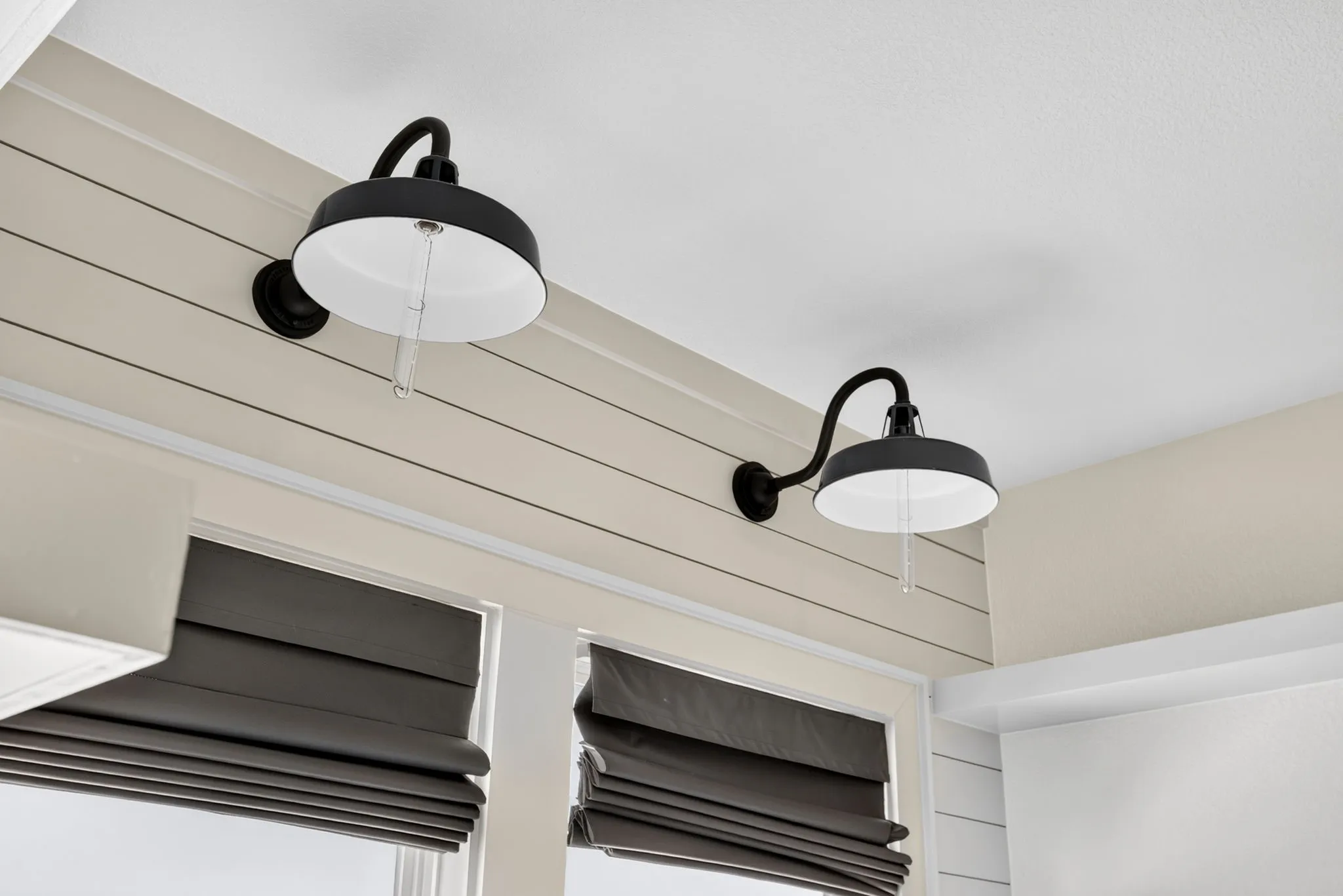 Two black barn-style wall sconces illuminate the shiplap accent wall