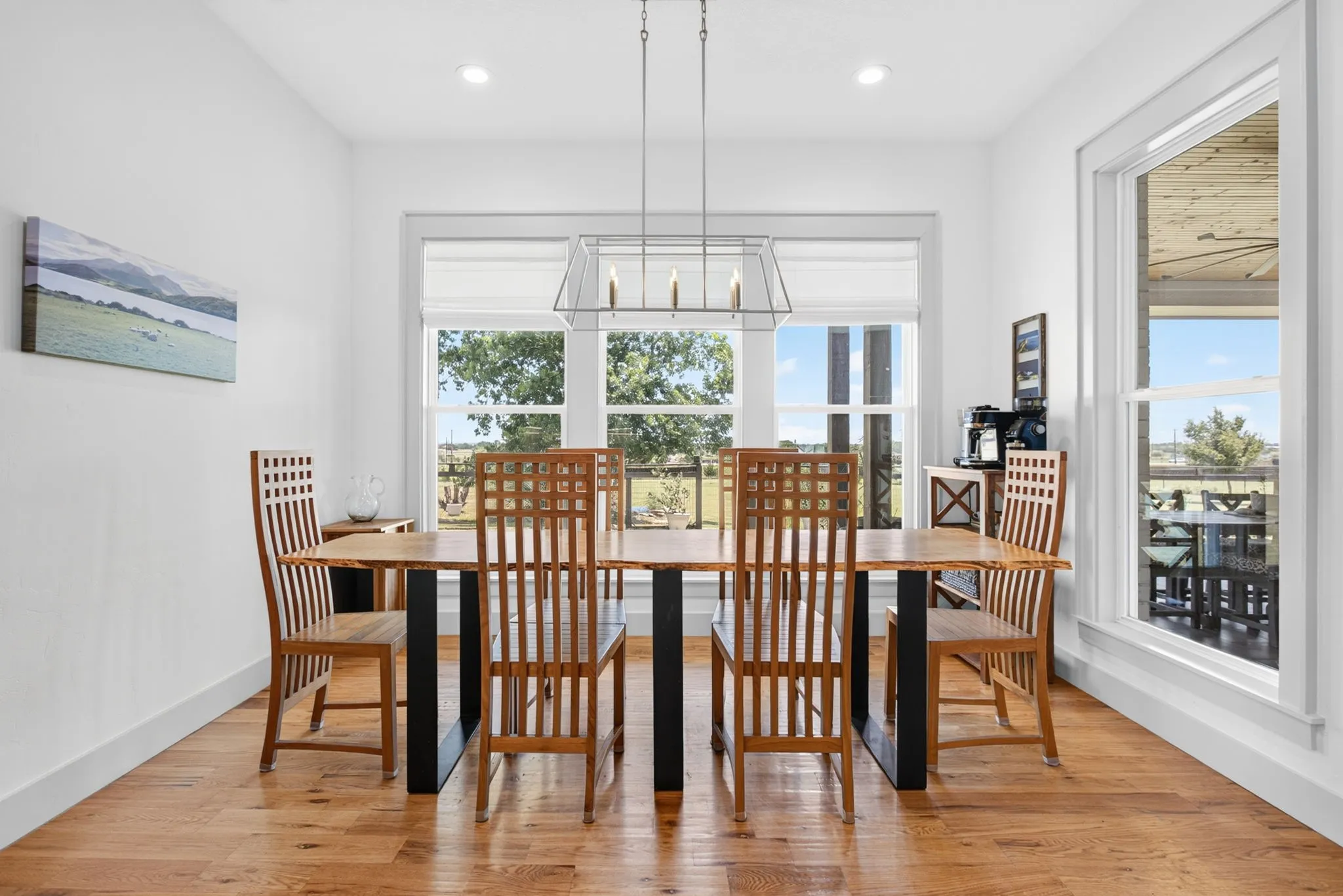 Dining area featuring wood-finish flooring, white walls, and a large window with a distant landscape visible