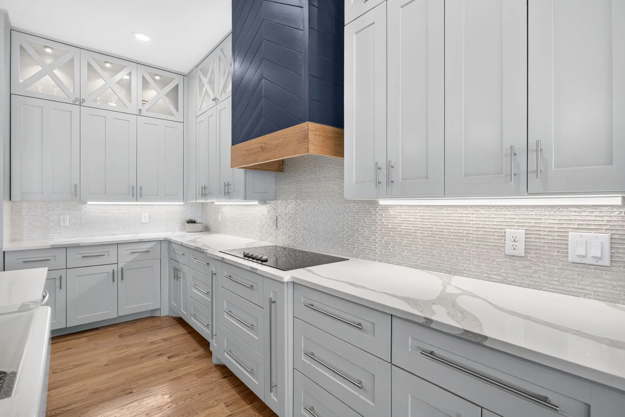 Spacious kitchen featuring light gray cabinetry, quartz countertops, a mosaic tile backsplash, and wood-finish flooring