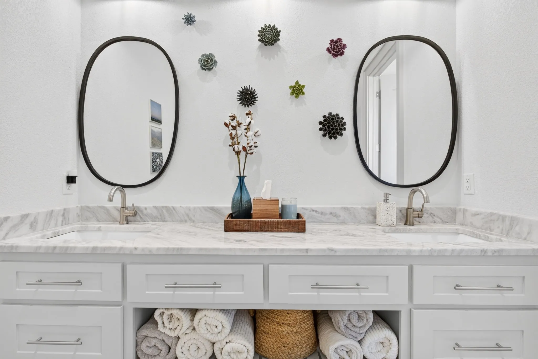 Double vanity featuring a marble-finish countertop, undermount sinks, and contemporary wall-mounted oval mirrors with black frames