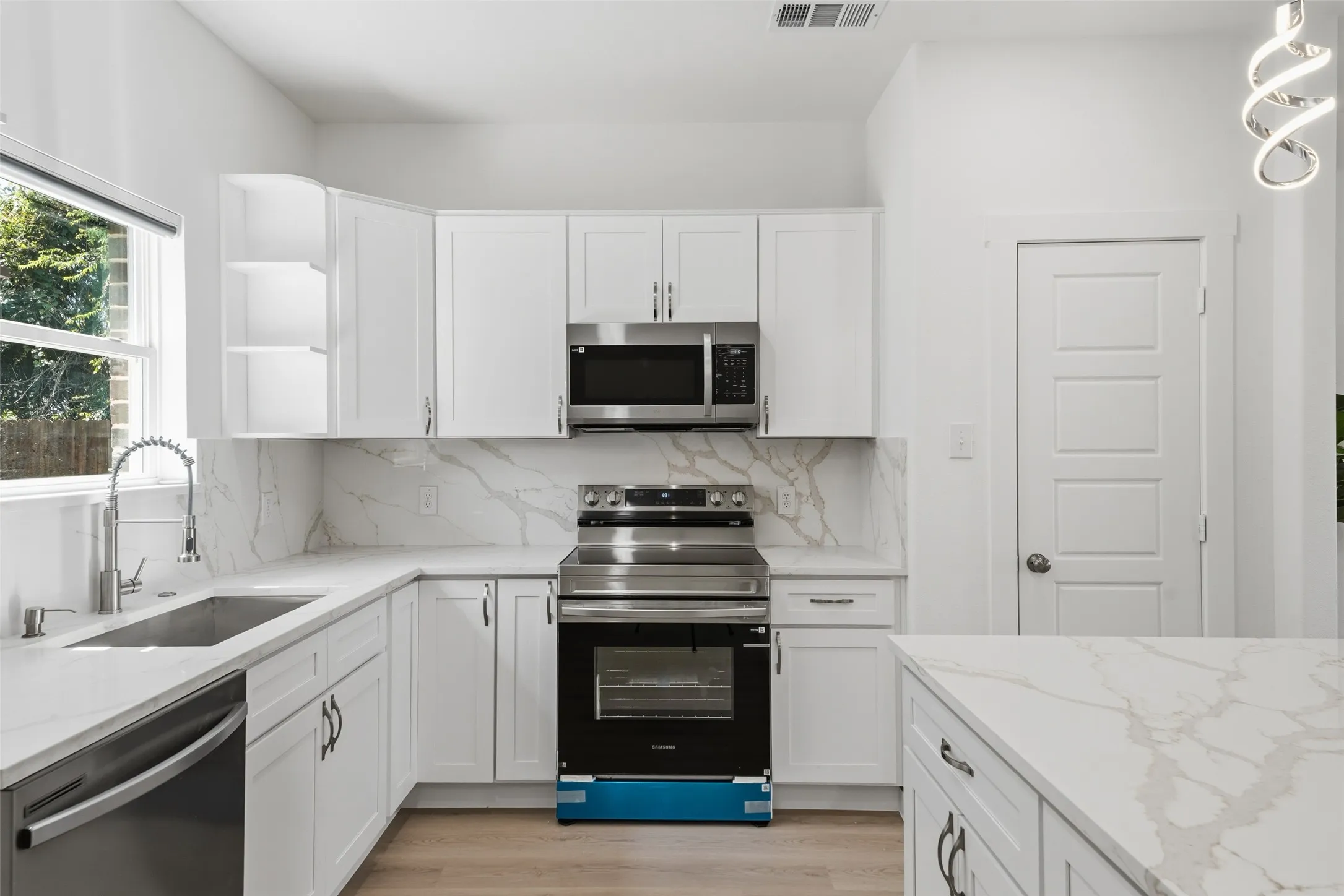 Modern kitchen featuring white shaker cabinetry and integrated stainless steel appliances