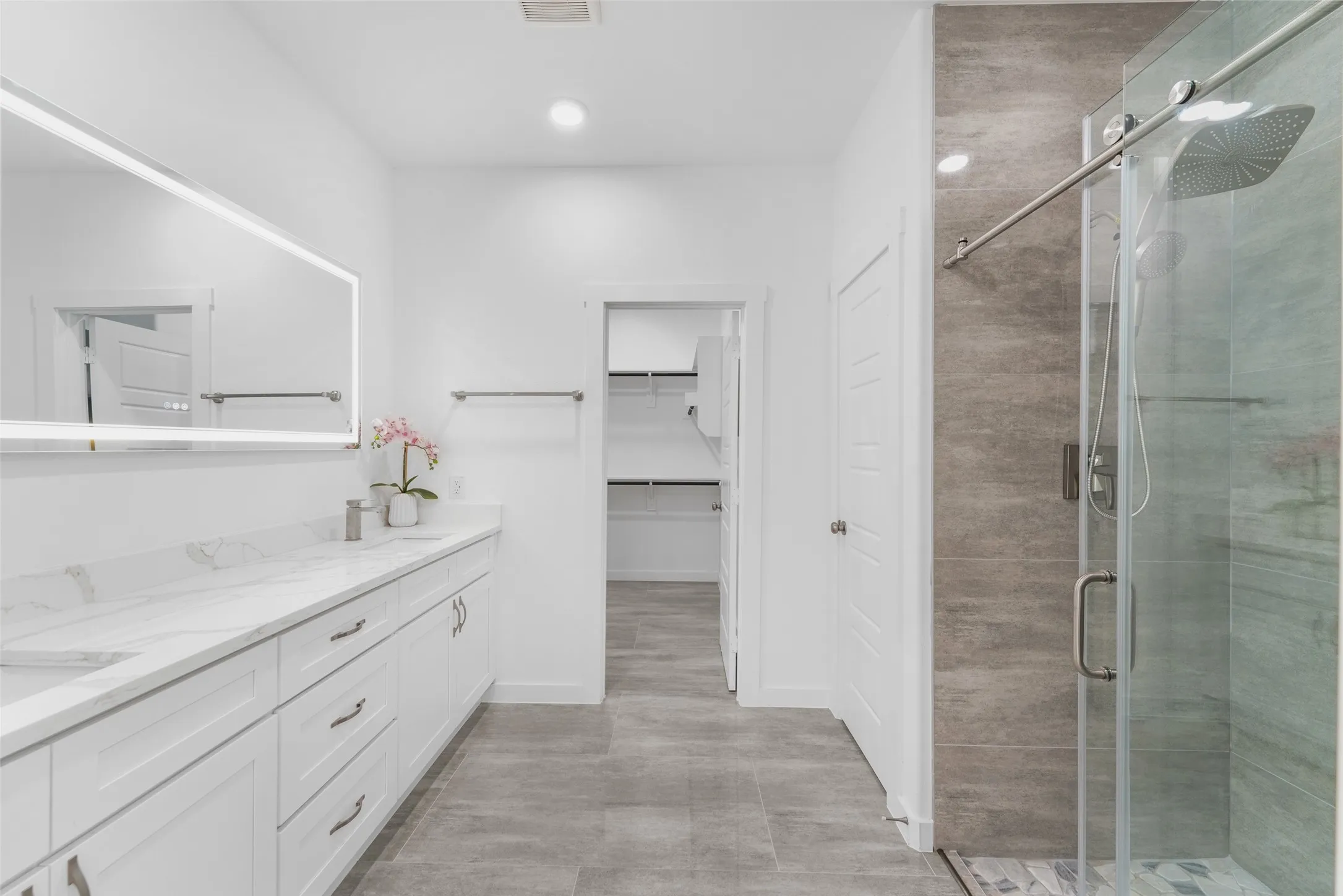 Contemporary bathroom featuring a spacious vanity with white cabinetry and a light-toned countertop