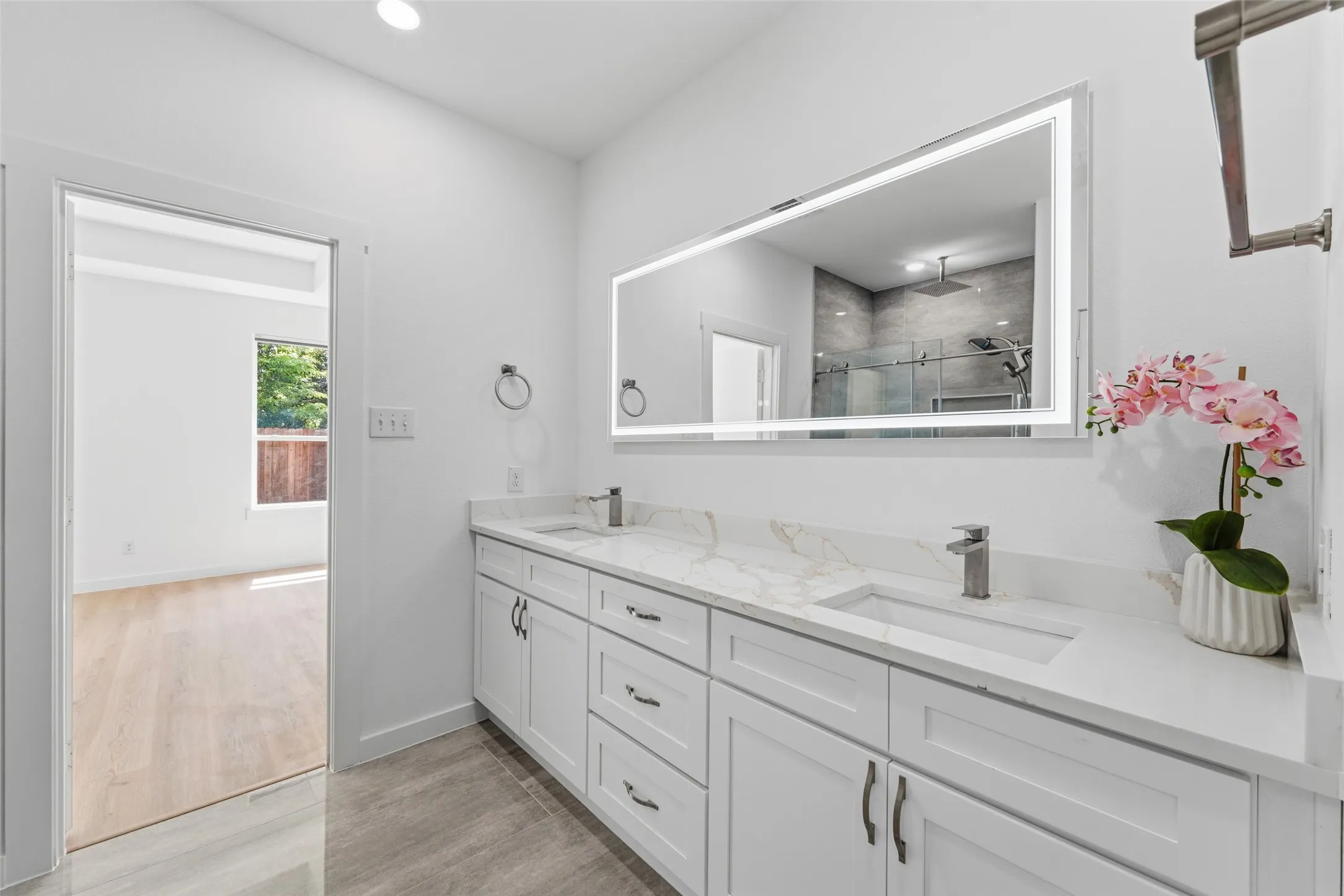 Bathroom featuring a dual vanity with white cabinetry, integrated sinks, and light-toned countertops