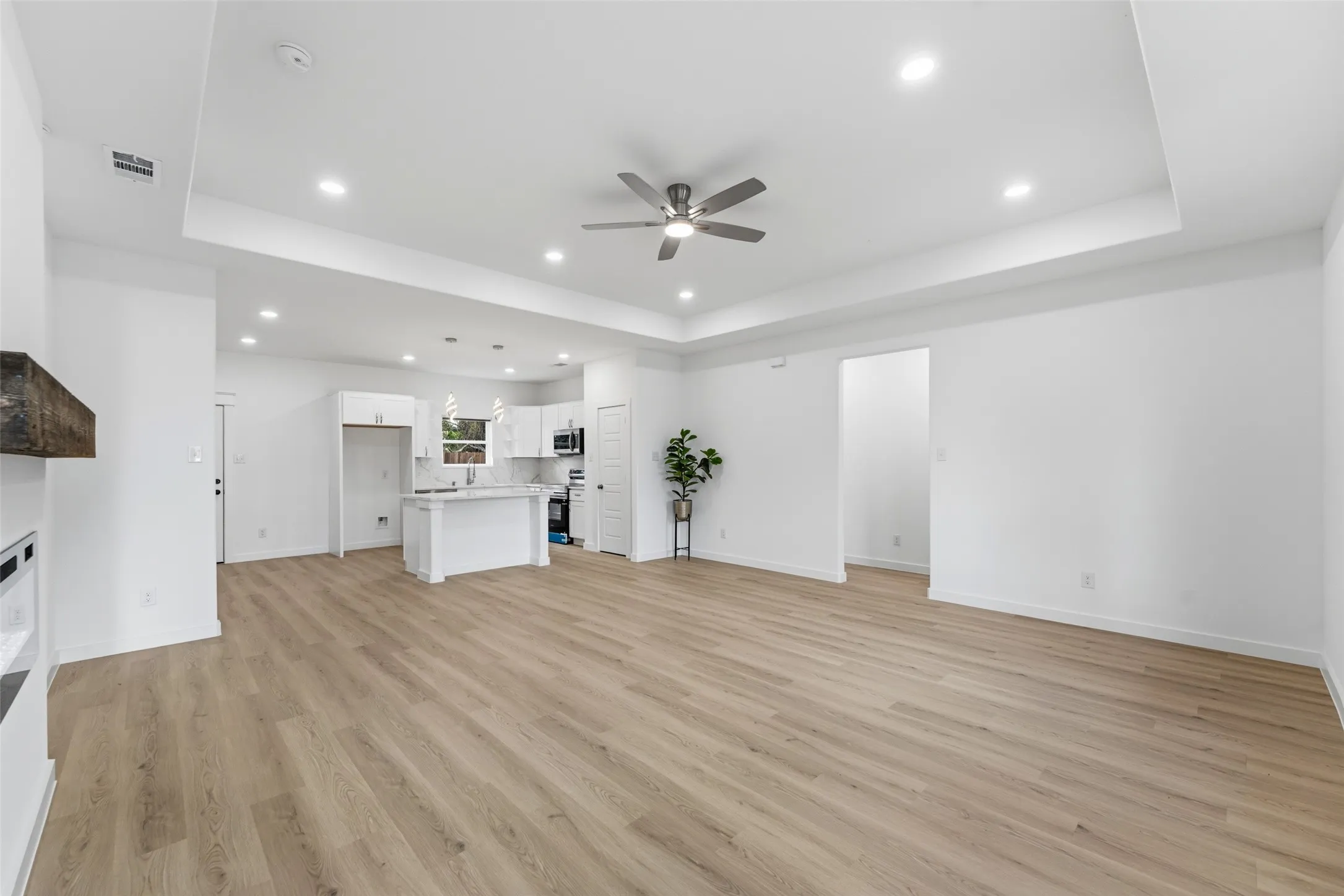 Expansive open-concept living area featuring light wood-finish flooring, a contemporary ceiling fan, and recessed lighting