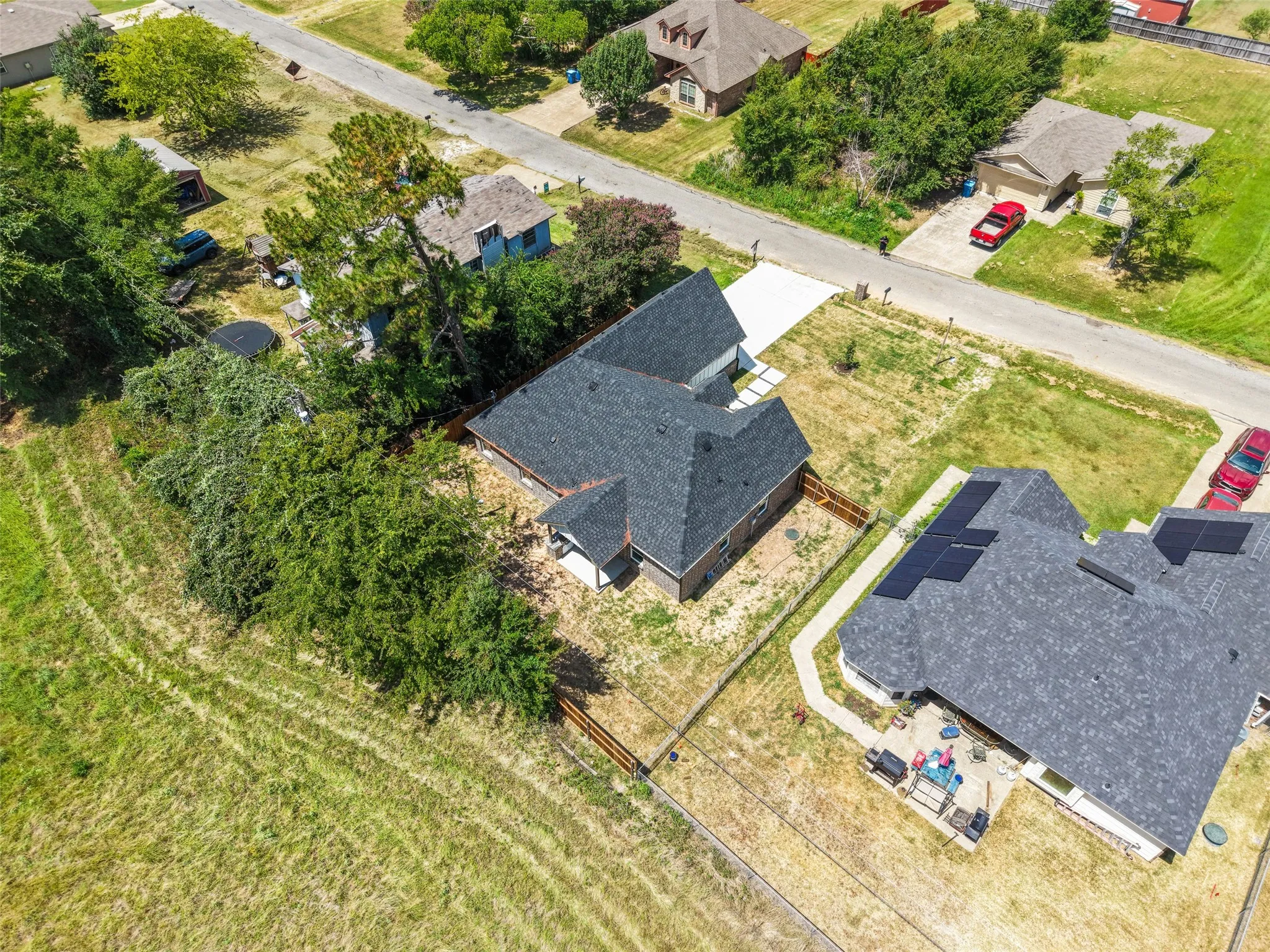 New construction residence featuring a dark shingle roof, light-colored concrete driveway, and surrounding green space