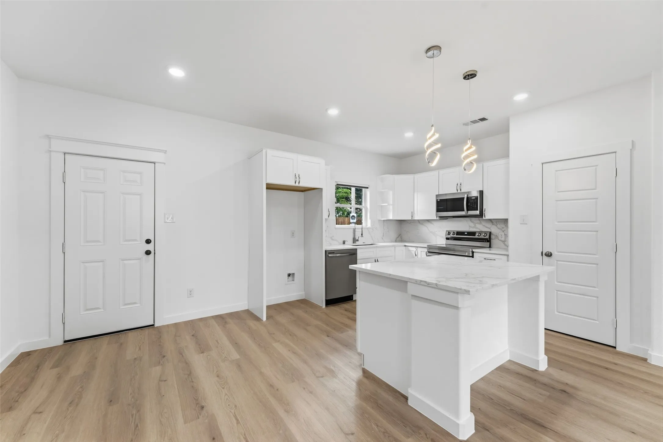 Open-concept kitchen and living area featuring wood-finish flooring, white cabinetry, a kitchen island with a stone countertop, and recessed lighting