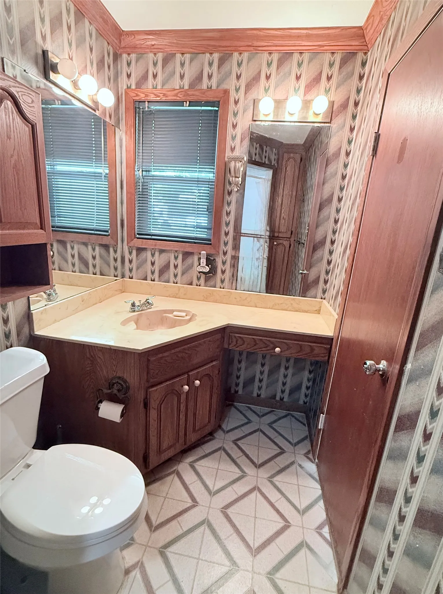 Bathroom featuring a corner vanity with a built-in sink, wood-finish cabinetry, and a countertop