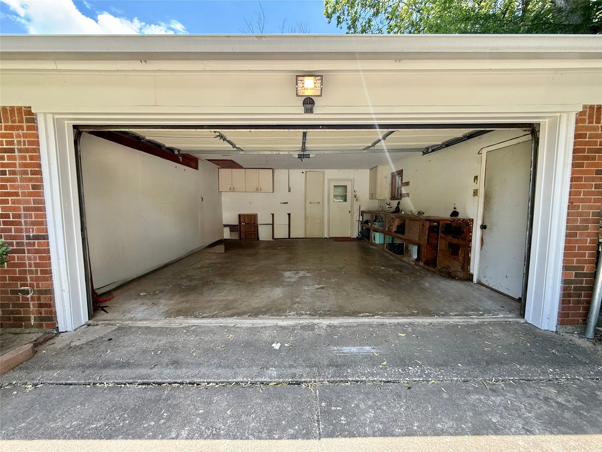 Two-car garage with concrete flooring, overhead lighting, and built-in cabinetry