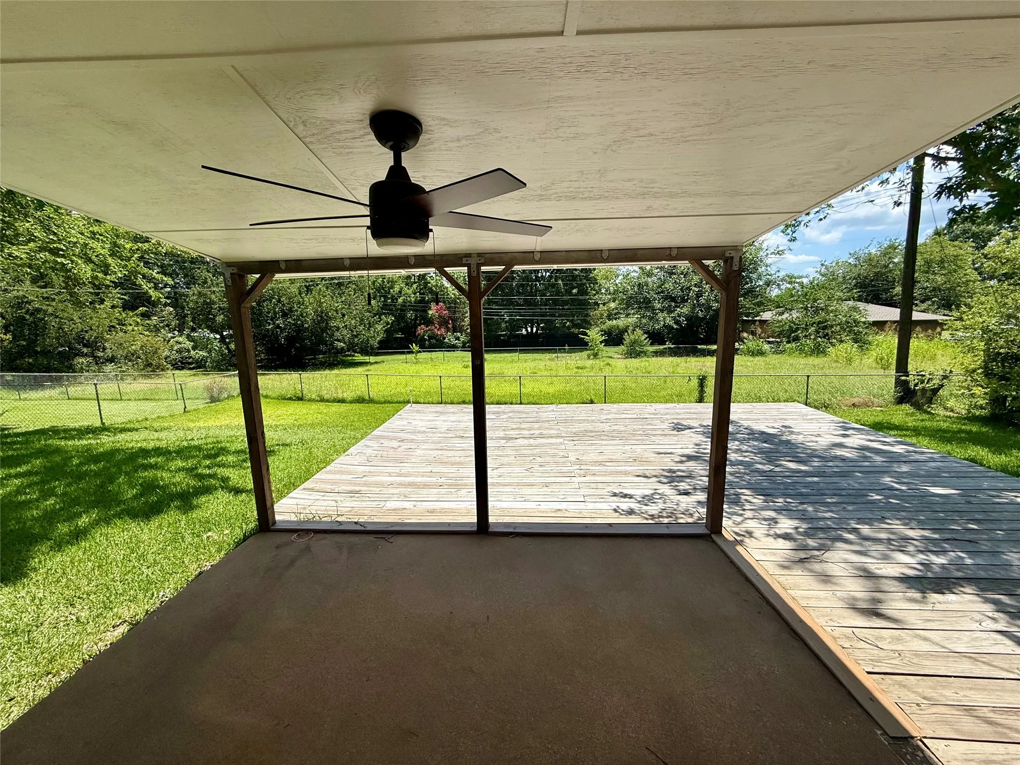 Covered patio with an integrated ceiling fan, extending to an open wood deck
