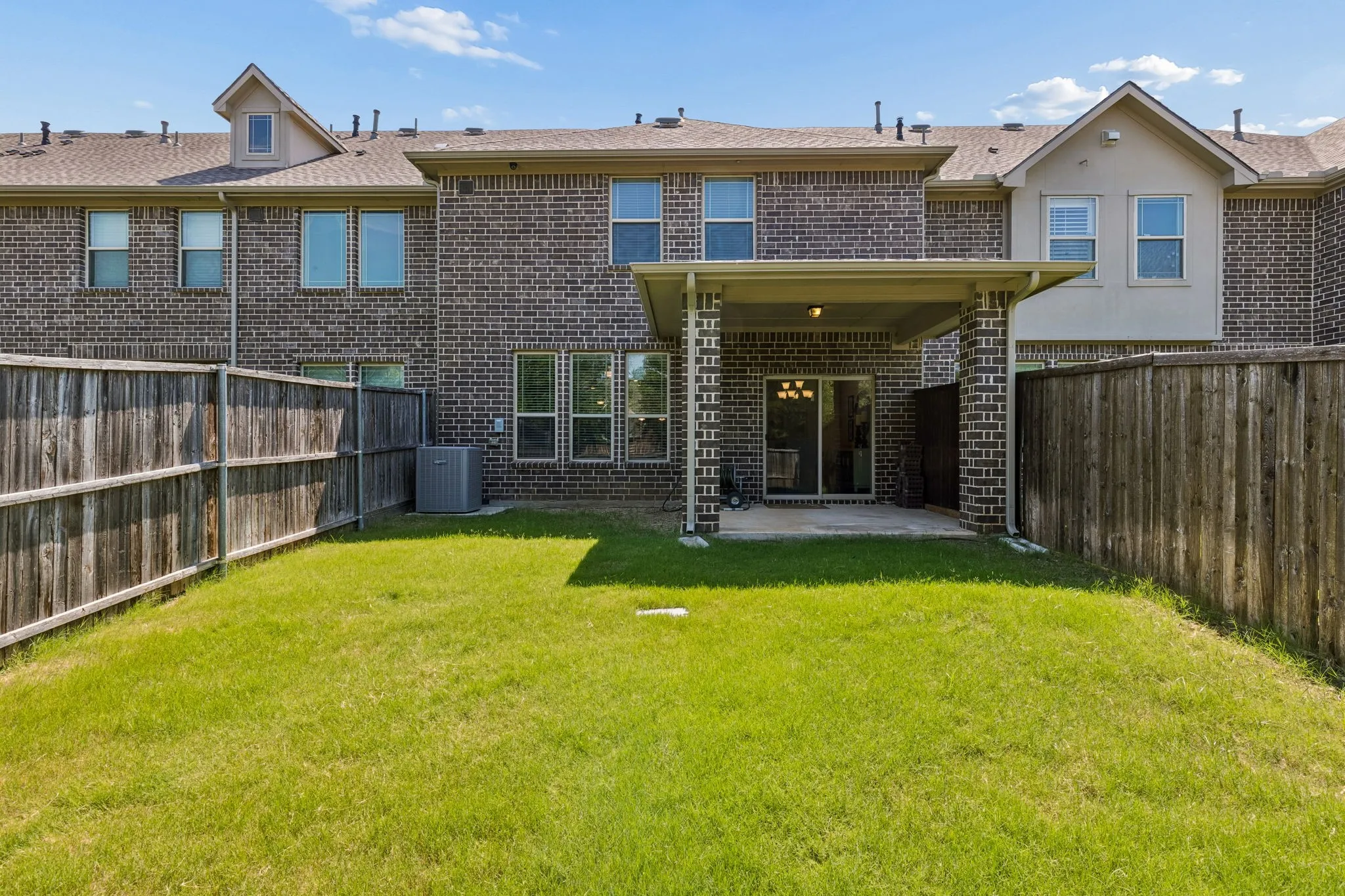 Private backyard with a covered patio, brick exterior, and a sliding glass door for indoor-outdoor living