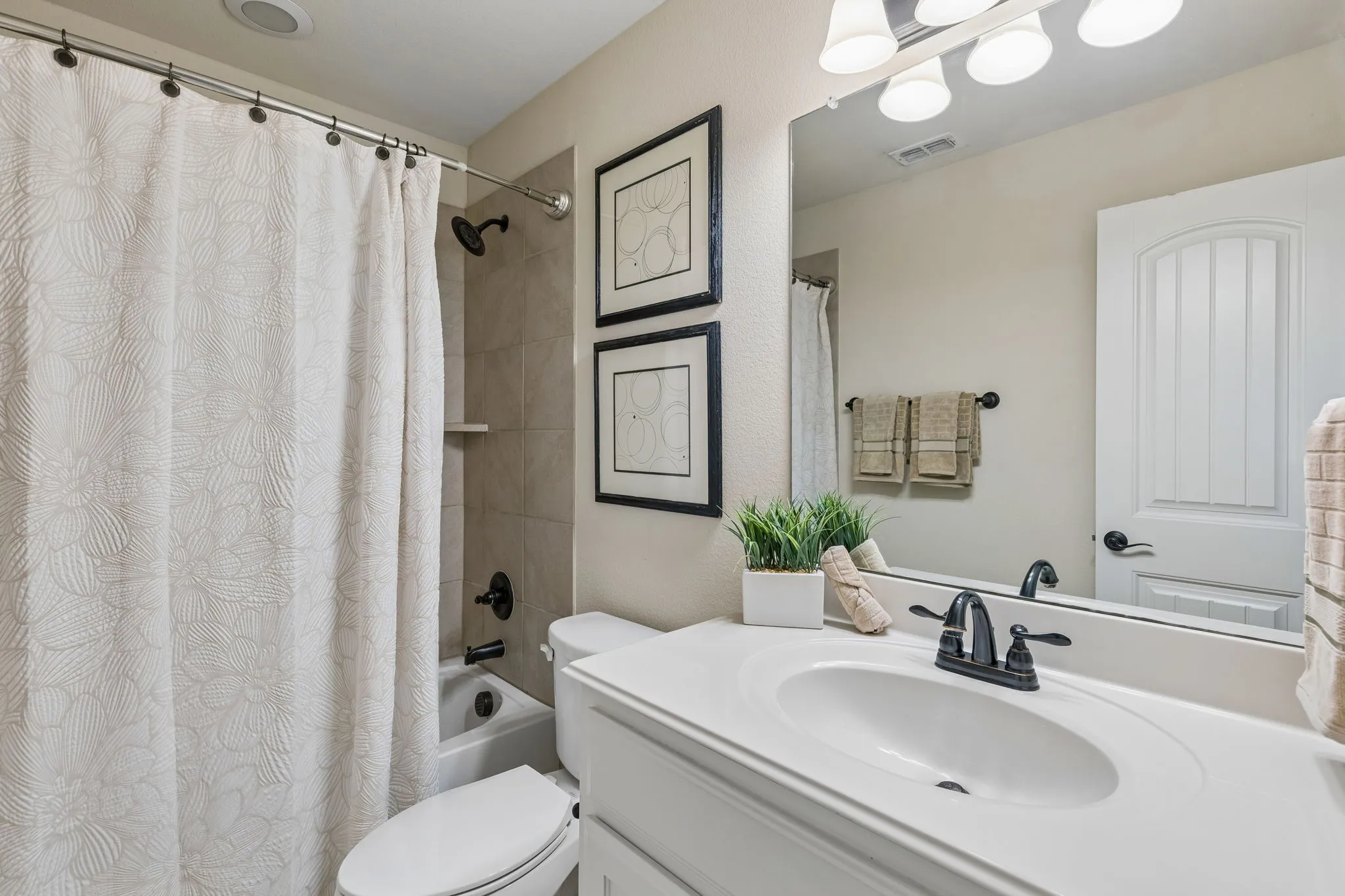 Bathroom featuring a white vanity with an integrated sink, black hardware, an overhead light fixture, and a framed mirror